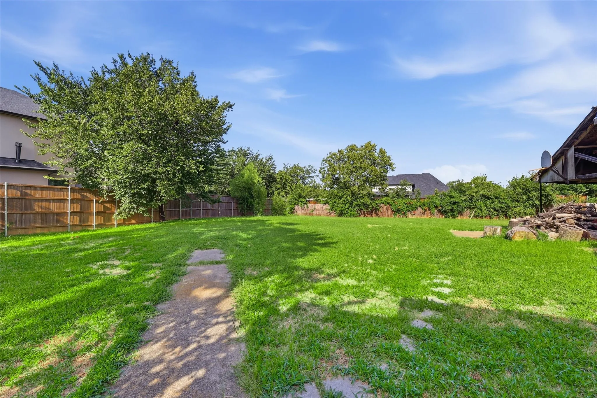 Expansive green lawn with mature trees and perimeter fencing