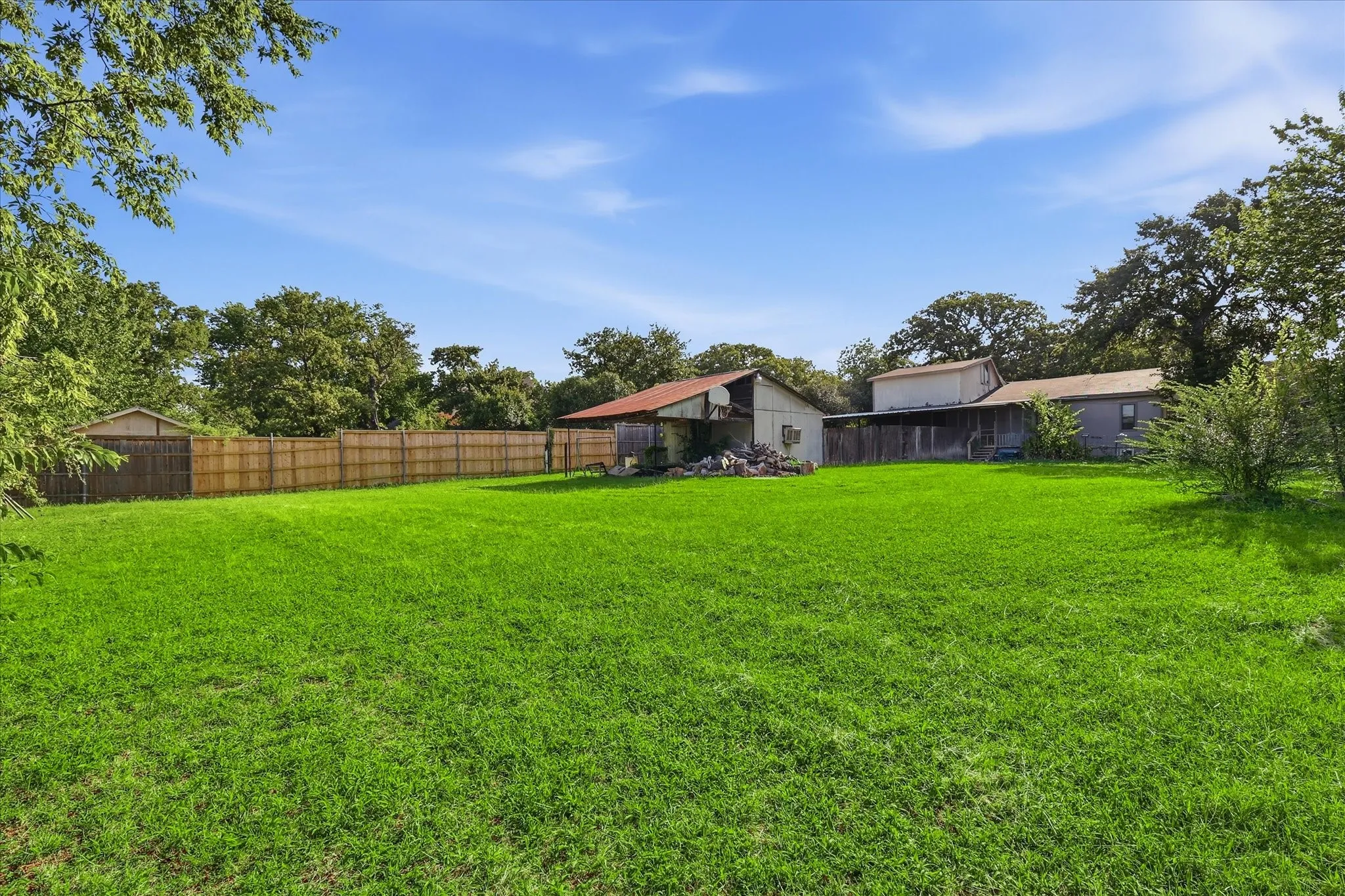 Expansive green lawn with mature trees bordering the property line