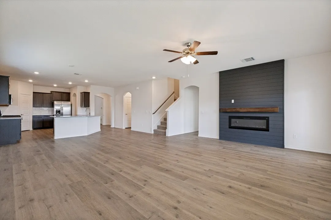 Spacious living area featuring wood-finish flooring, a contemporary fireplace with a shiplap accent wall, and recessed lighting