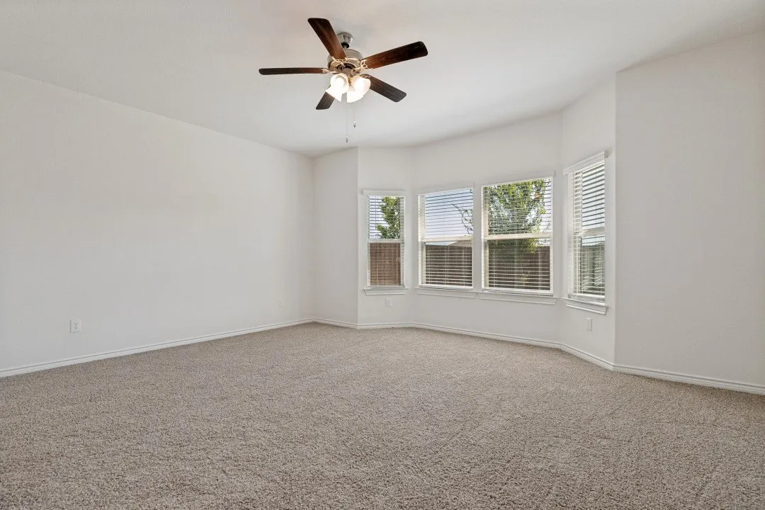 Spacious room featuring neutral carpeting, light-toned walls, and a bay window with multiple panes