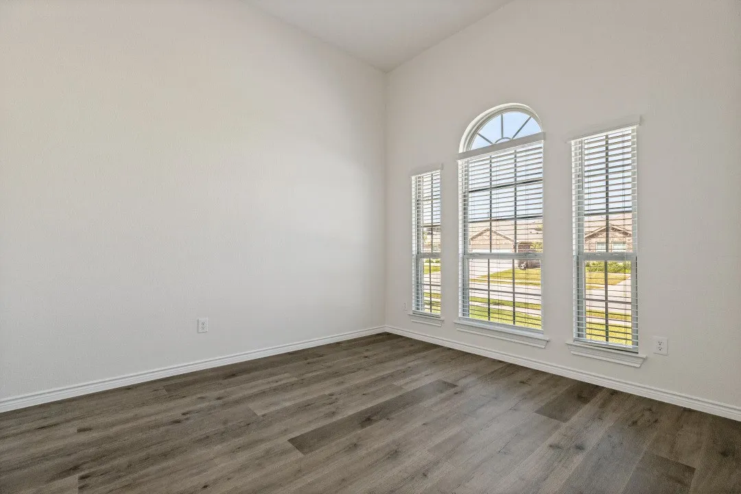 Room featuring a vaulted ceiling and wood-finish flooring