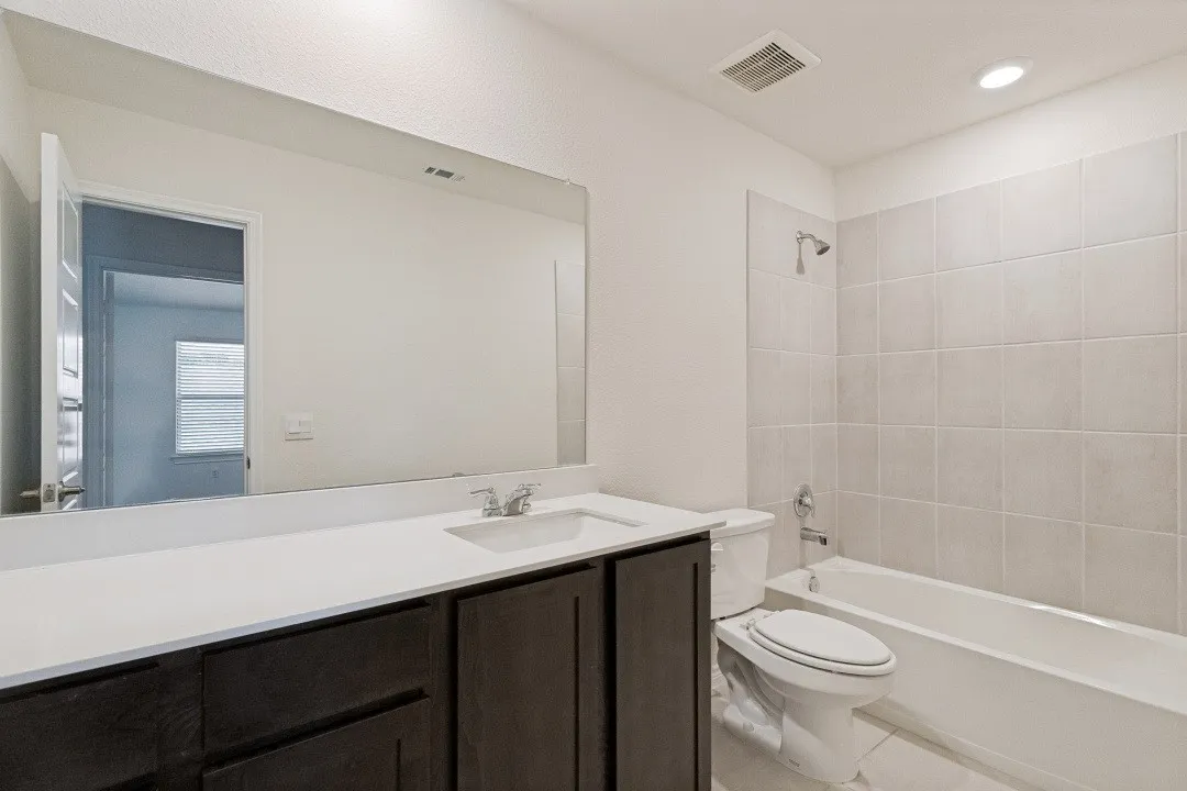 Bathroom featuring a single vanity with dark wood-finish cabinetry, a white countertop, and a large wall-mounted mirror