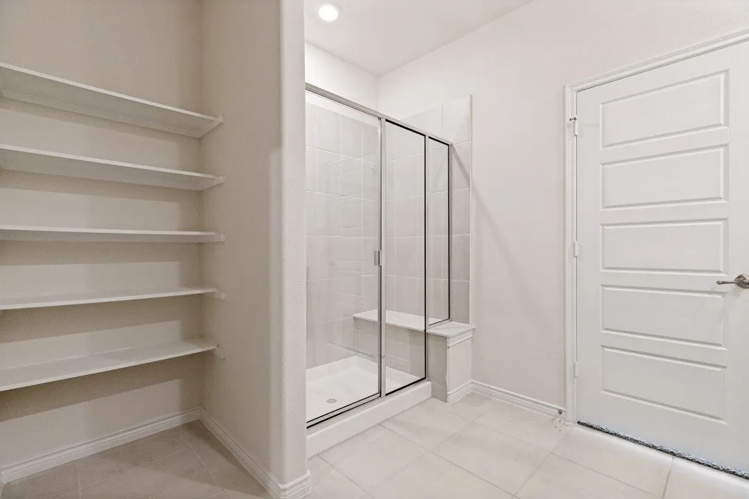 Walk-in shower with clear glass enclosure and integrated bench seating