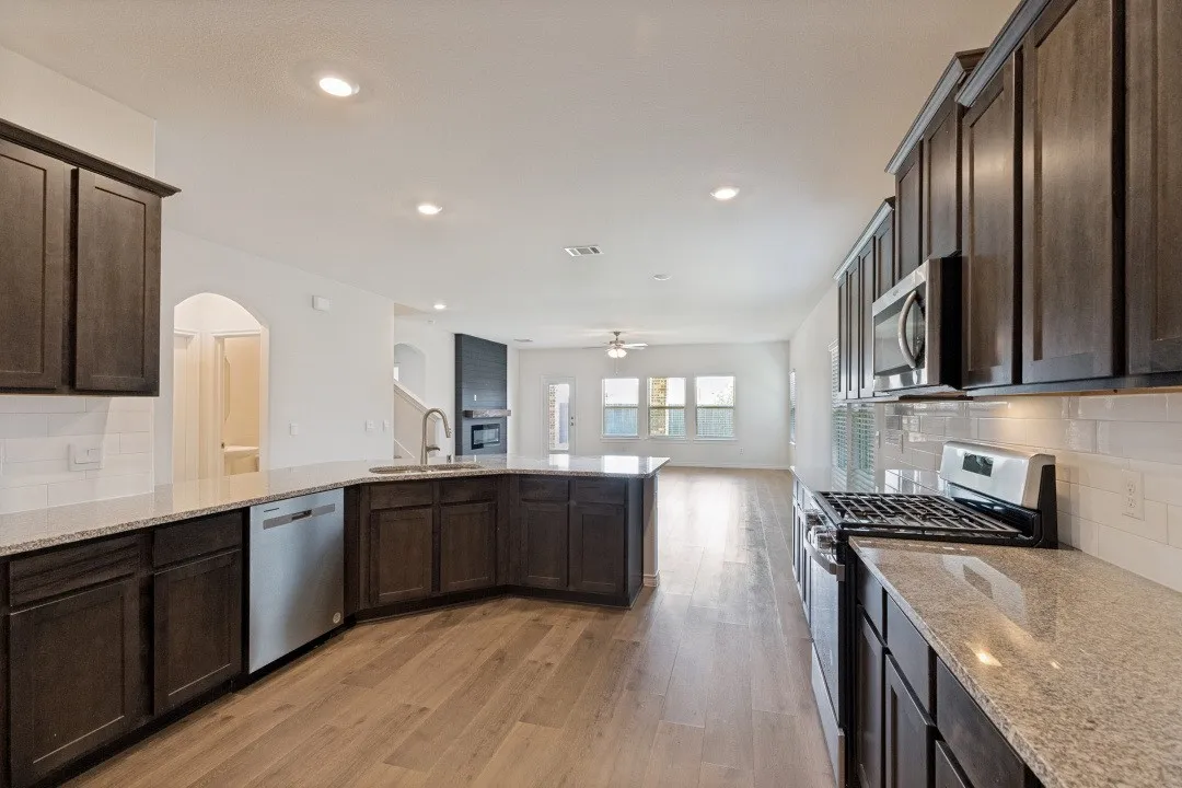 Spacious kitchen featuring dark wood cabinetry, light-toned countertops, and stainless steel appliances