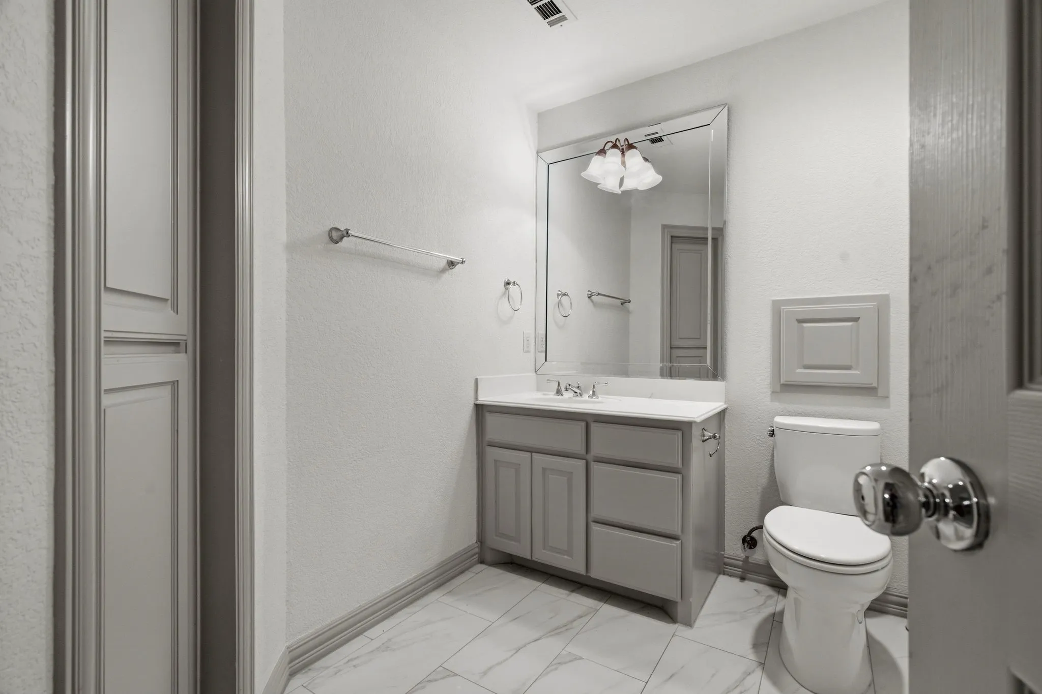 Bathroom featuring a gray vanity with an undermount sink, a framed mirror, and a white countertop