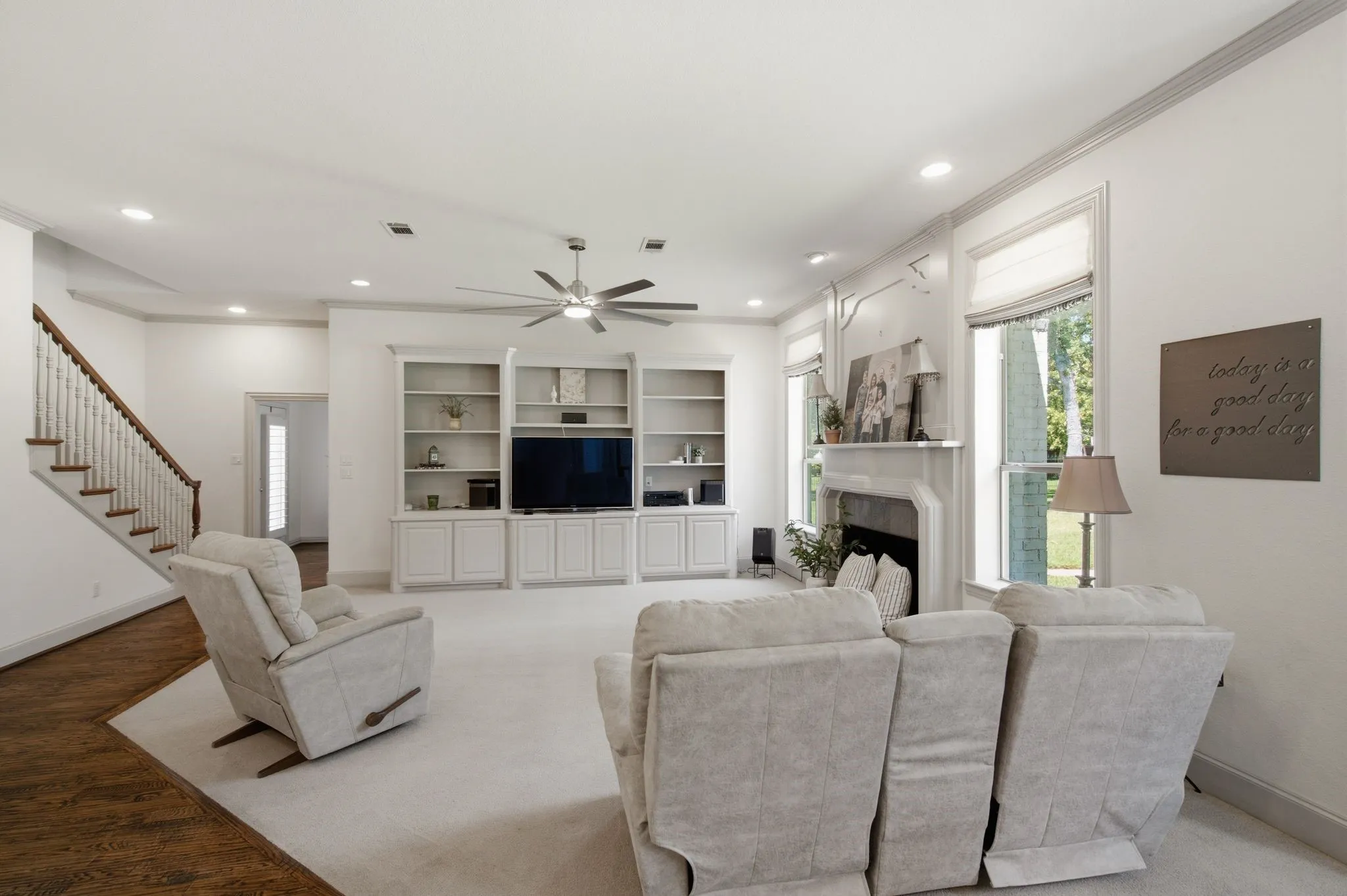 Living area featuring a fireplace with a detailed mantel, built-in shelving, recessed lighting, a ceiling fan, and wood-finish flooring