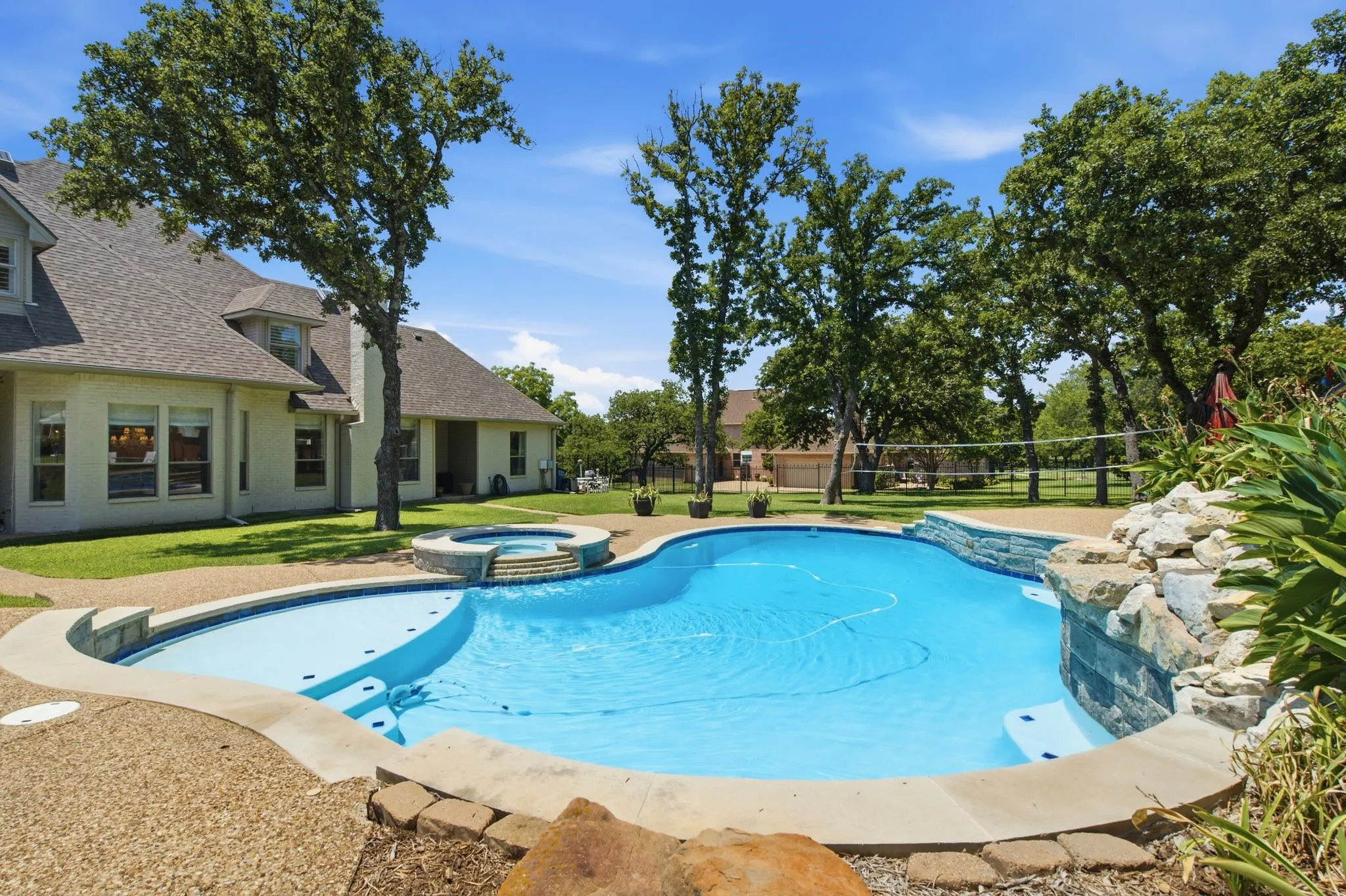 Freeform swimming pool with integrated spa and rock waterfall feature