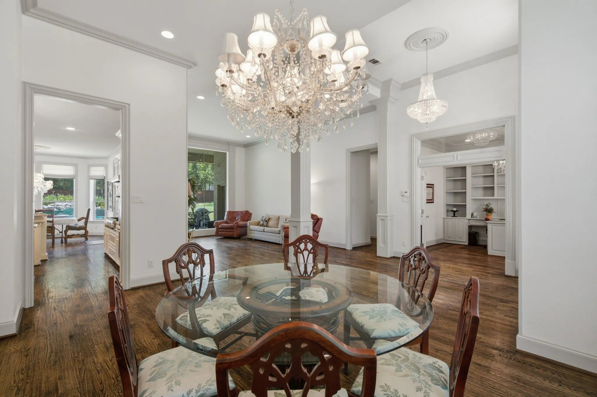 Hardwood flooring throughout featuring a large crystal chandelier, recessed lighting, crown molding, and built-in shelving