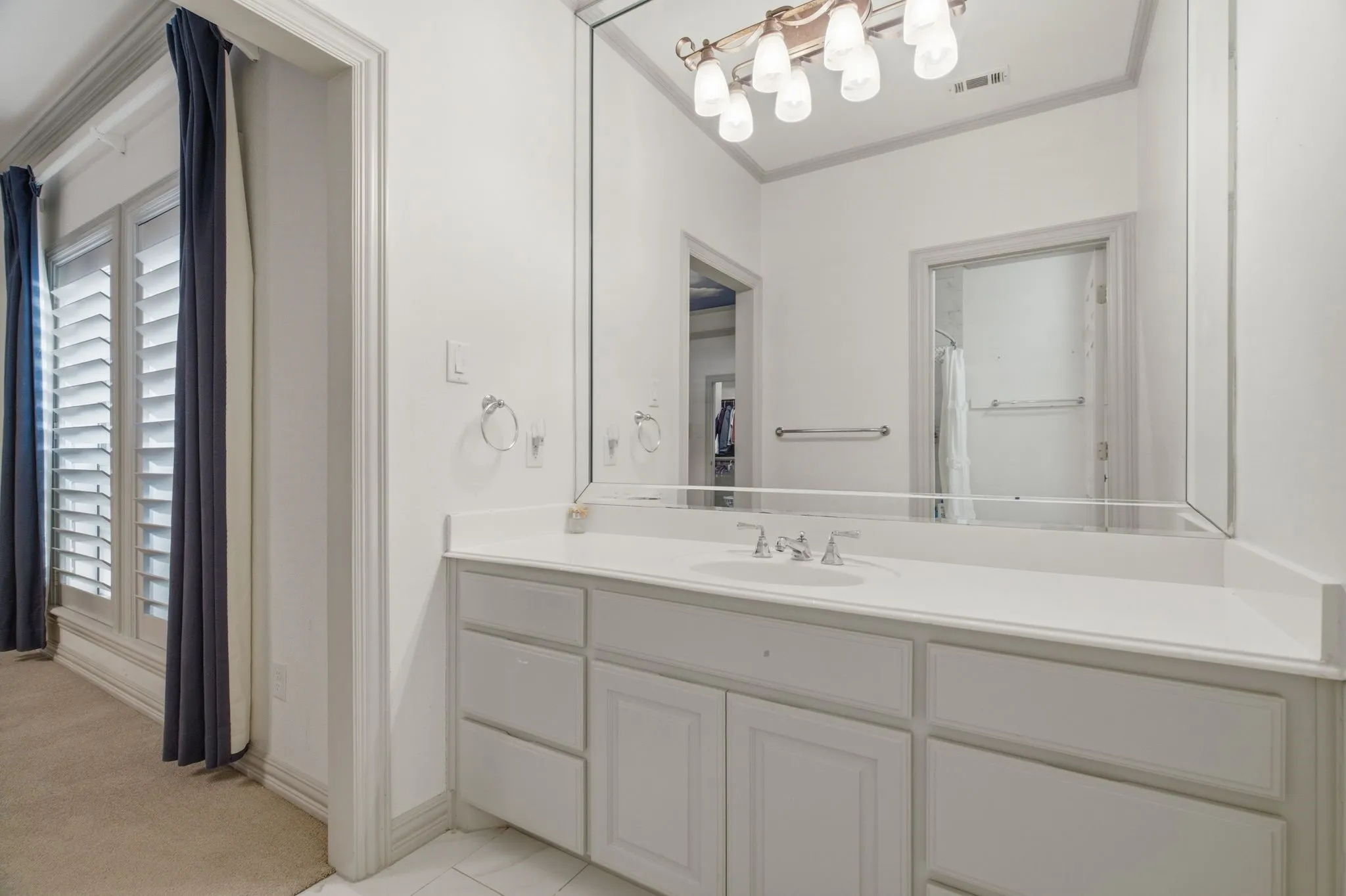 Vanity with a single undermount sink, a chrome faucet, and white countertop