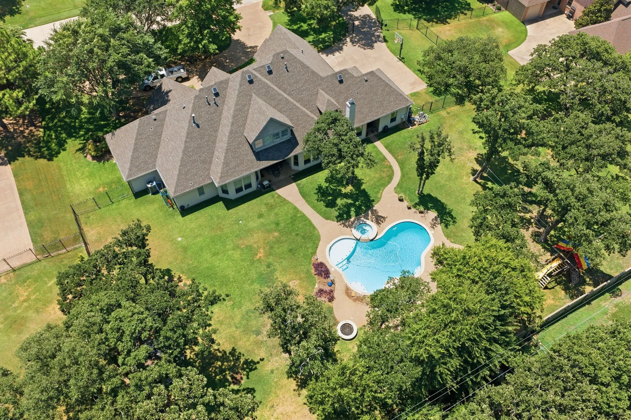 Expansive property featuring a freeform swimming pool with integrated spa, surrounded by a hardscape patio
