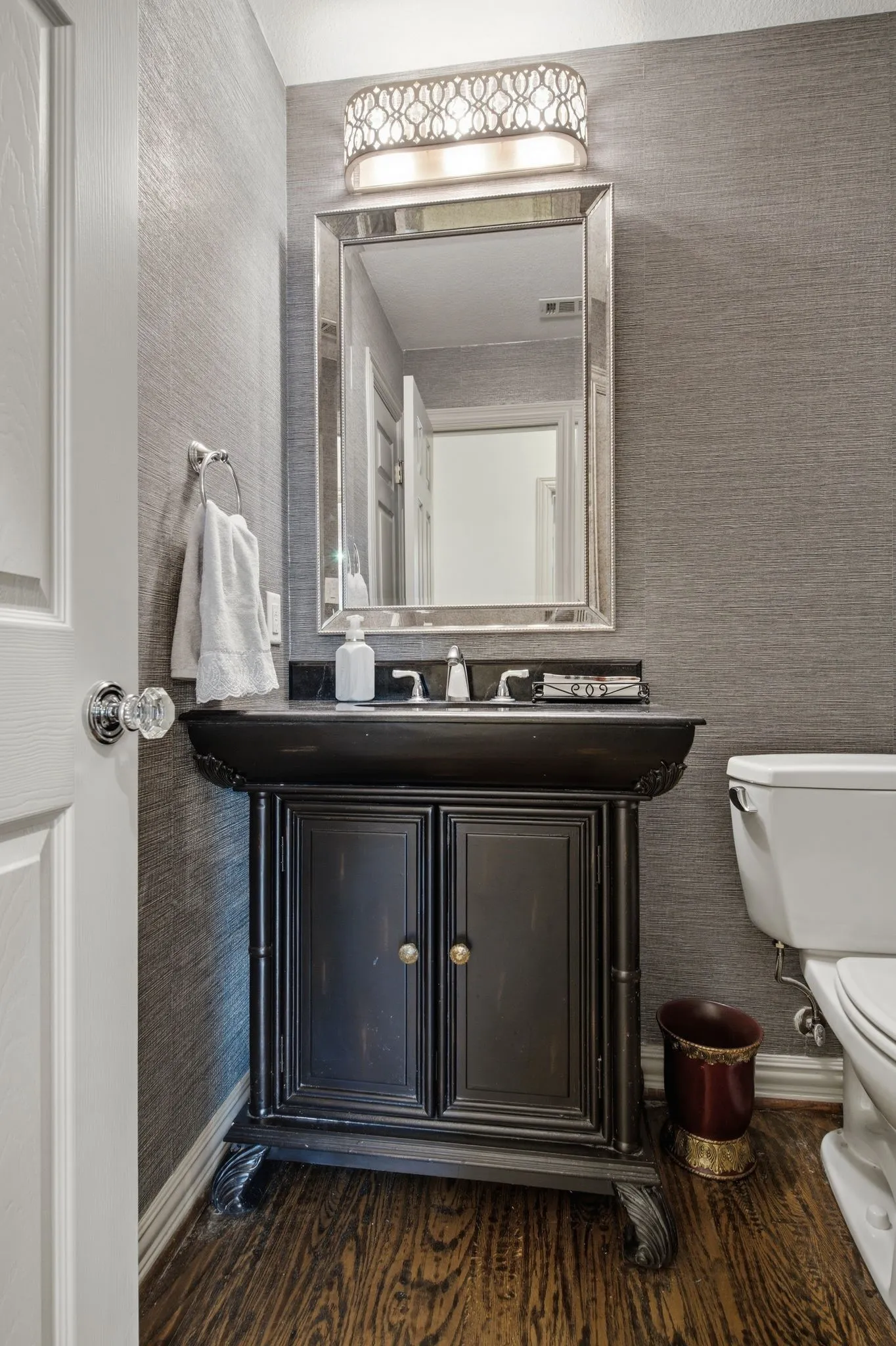 Vanity with distressed black finish and integrated basin, set against textured wall covering