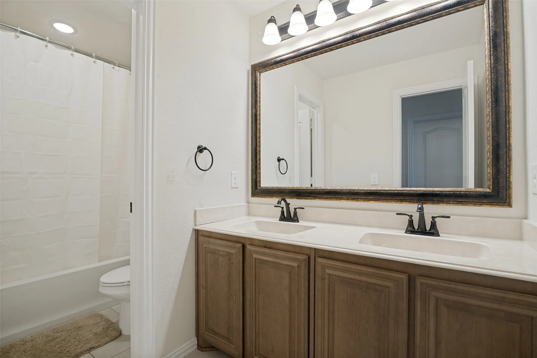 Double vanity with light countertops and wood-finish cabinetry