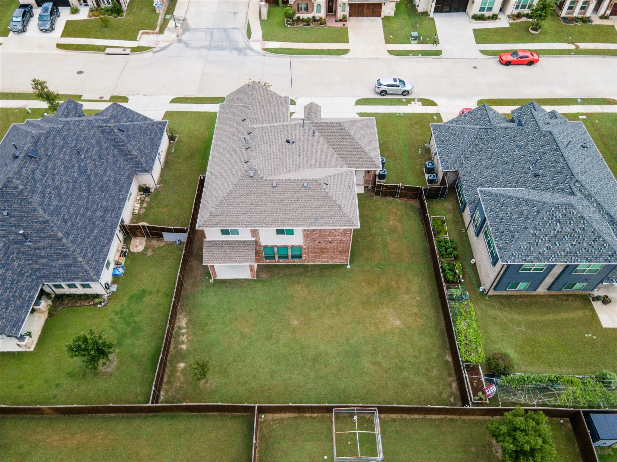Expansive rear yard featuring a manicured lawn, established perimeter fencing, and a dedicated garden area