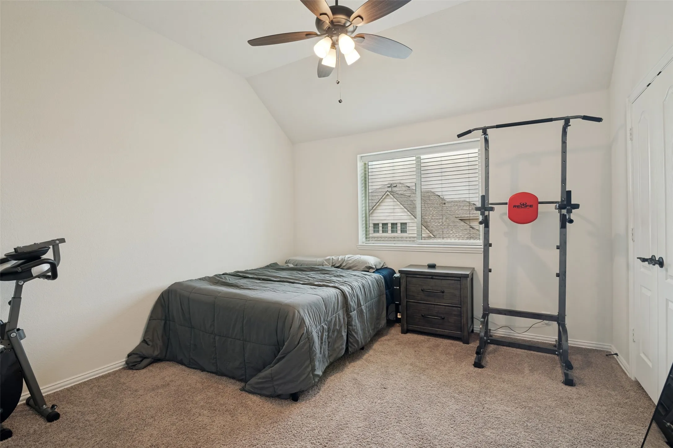 Carpeted room featuring a ceiling fan with integrated lighting, a window with horizontal blinds, and a white paneled door with dark hardware