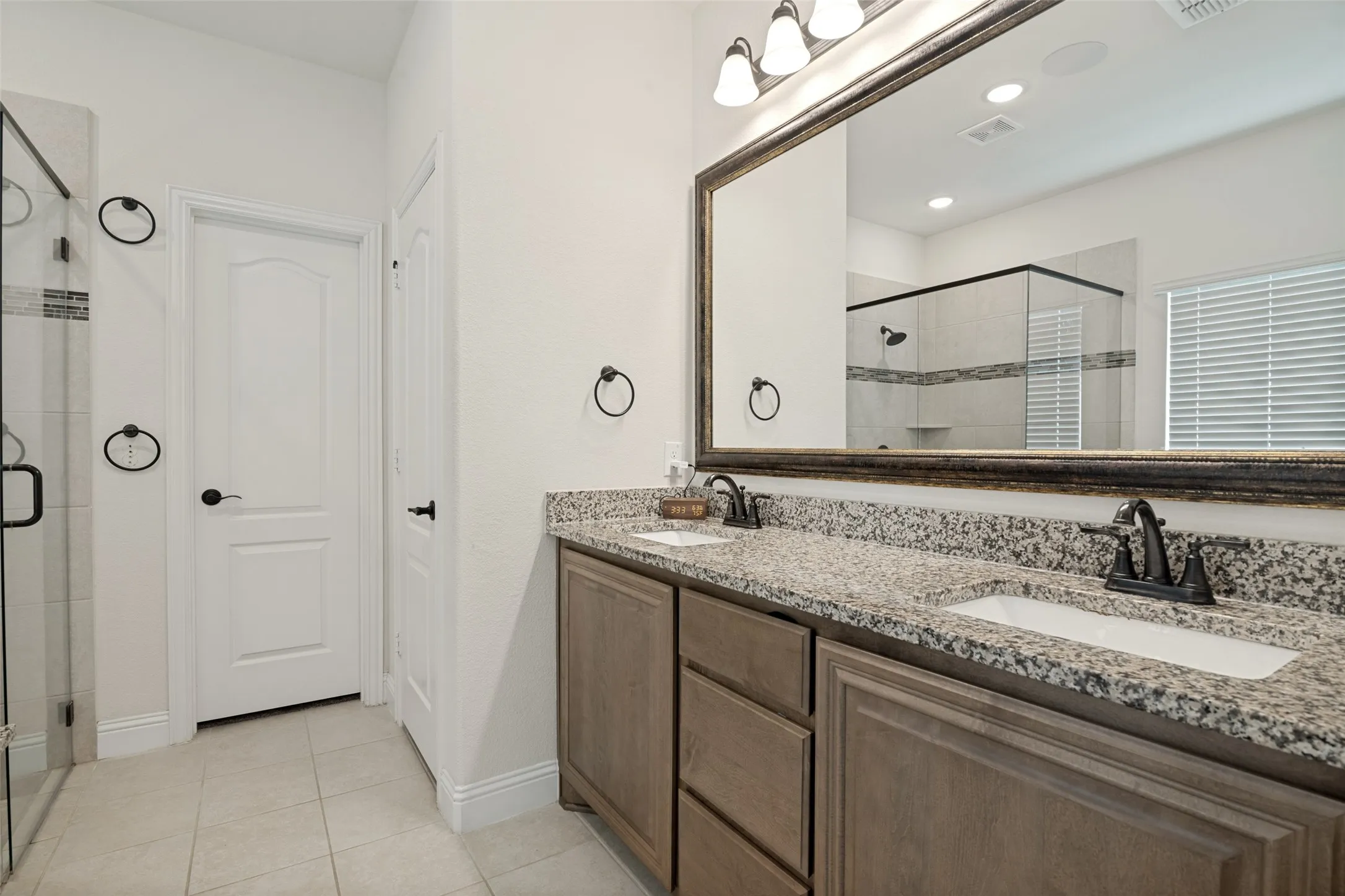 Dual vanity featuring a granite countertop with integrated sinks and dark bronze hardware
