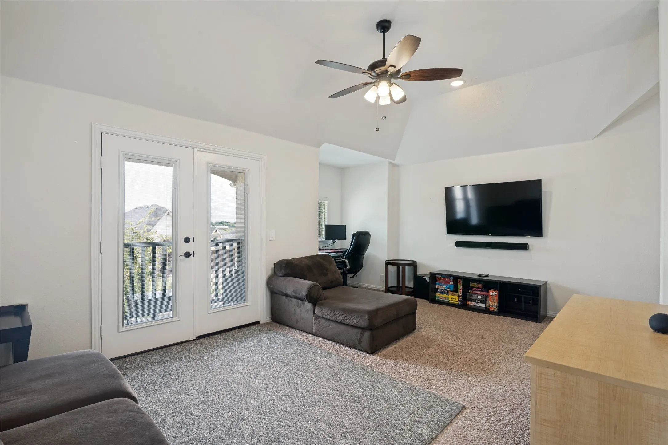 Spacious room featuring vaulted ceilings, a ceiling fan with integrated lighting, and carpet flooring