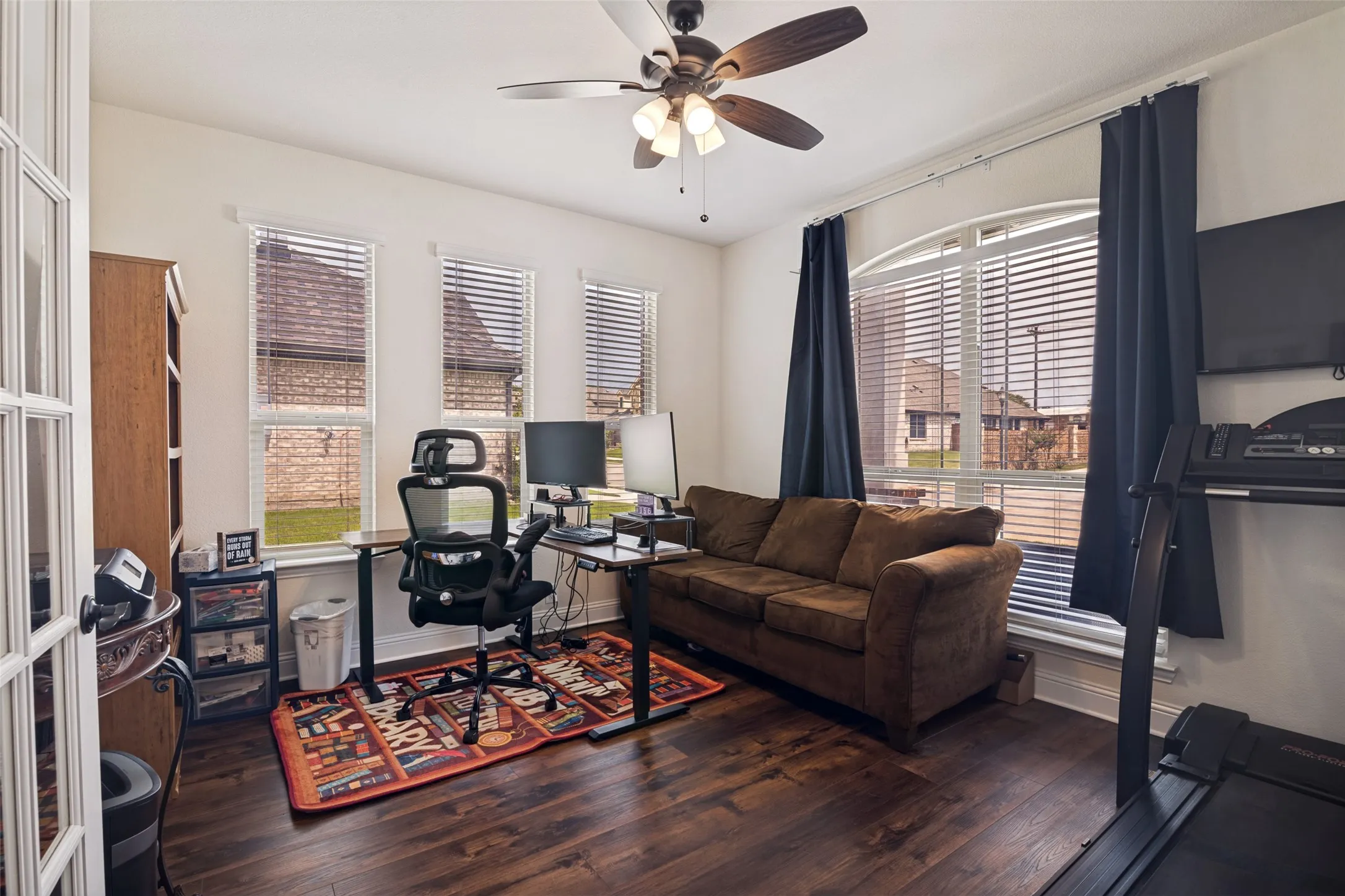 Room with wood-finish flooring, white walls, and a ceiling fan with light fixture