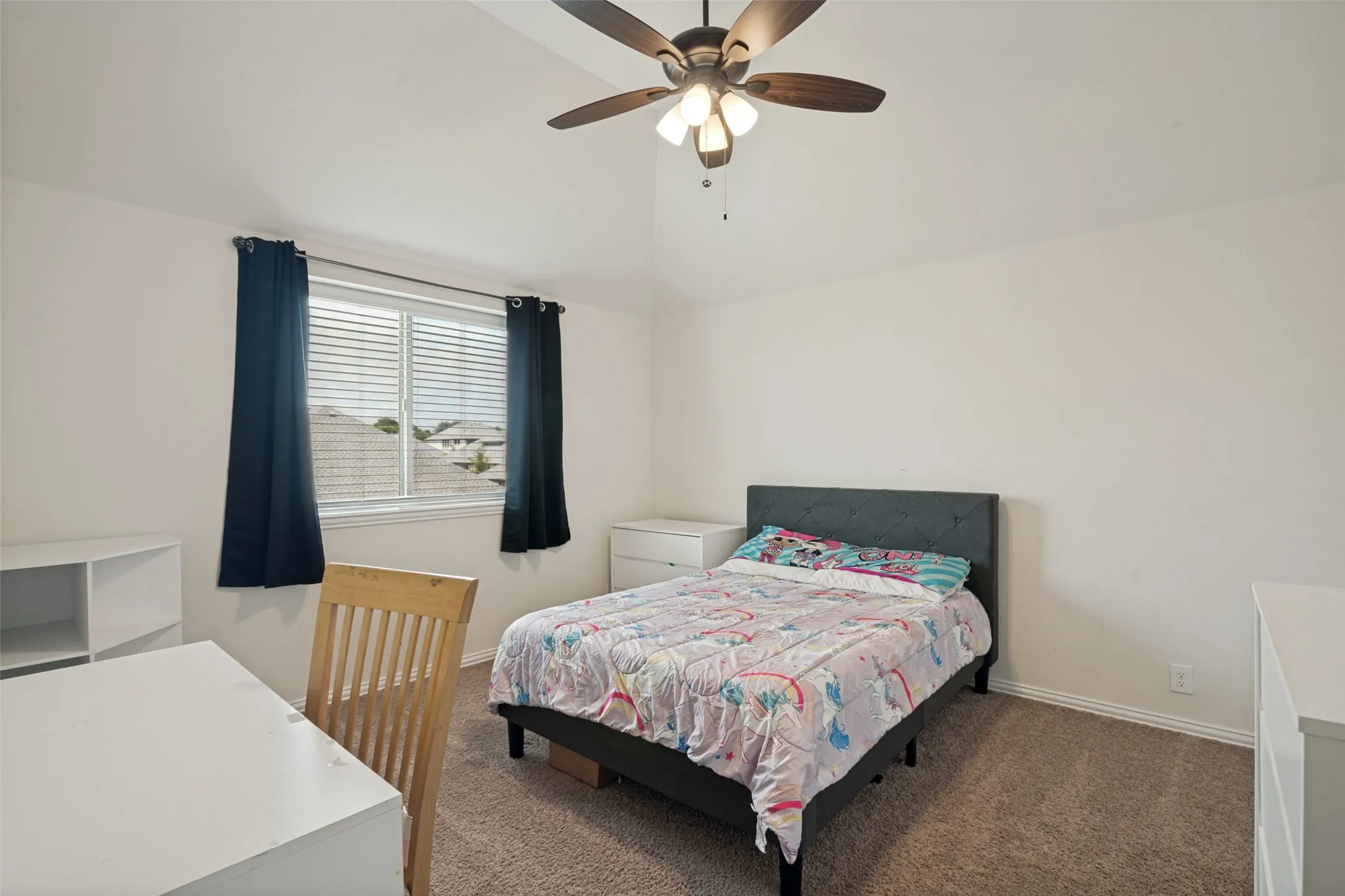 Carpeted room with a vaulted ceiling and a ceiling fan with light fixture