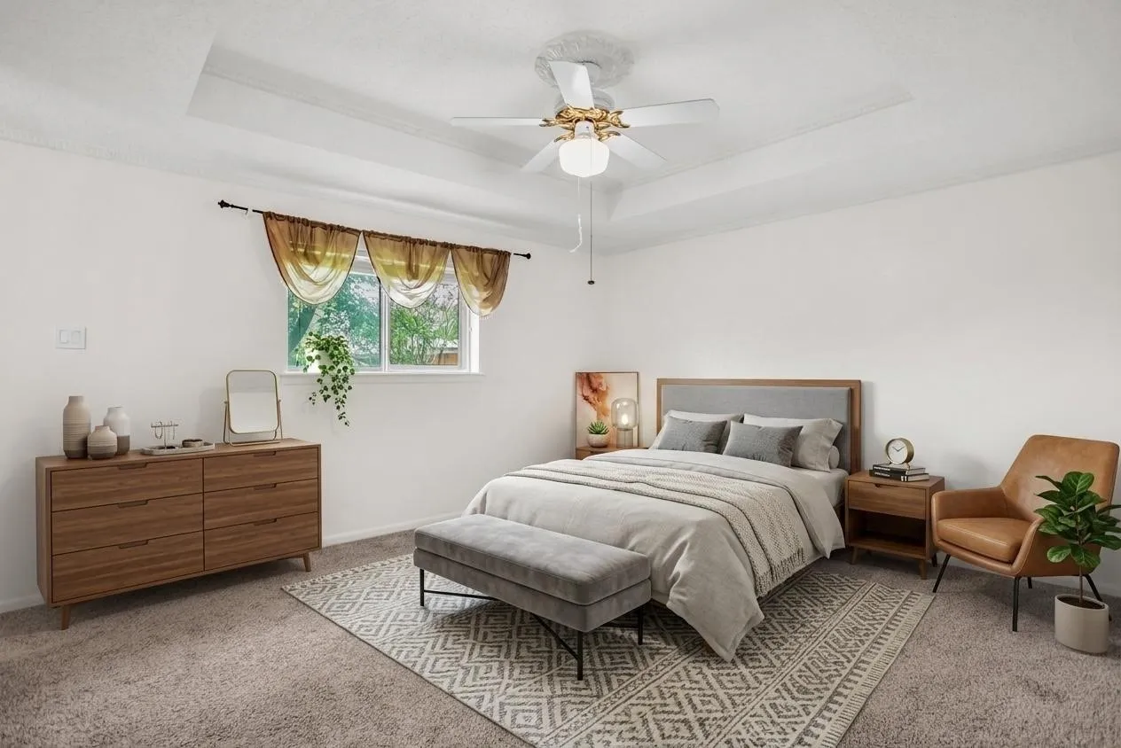 Recessed tray ceiling with crown molding, window with outdoor scenery, and ceiling fan with light fixture