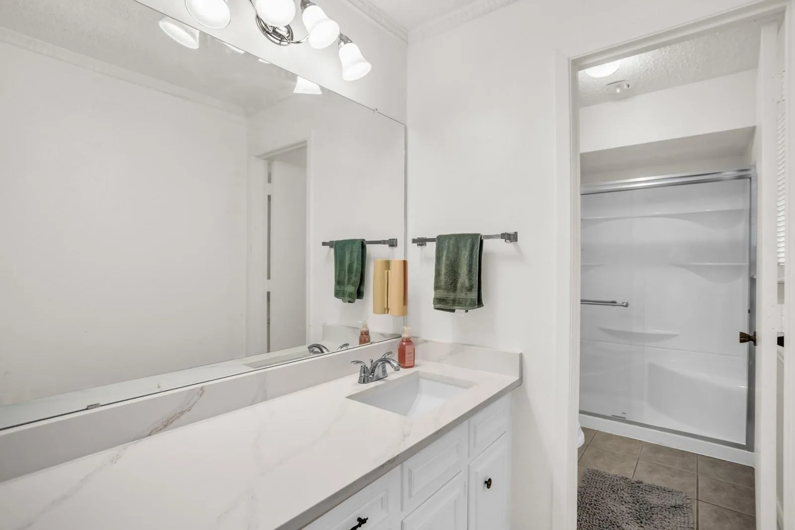 Bathroom featuring an extended vanity with a solid surface countertop, integrated sink, and white cabinetry