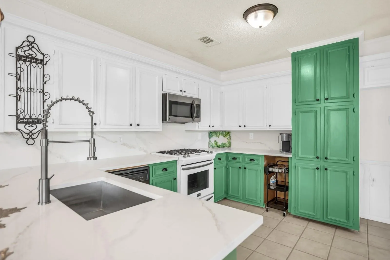 Kitchen featuring white upper cabinetry, green lower cabinetry, and a tall green pantry cabinet