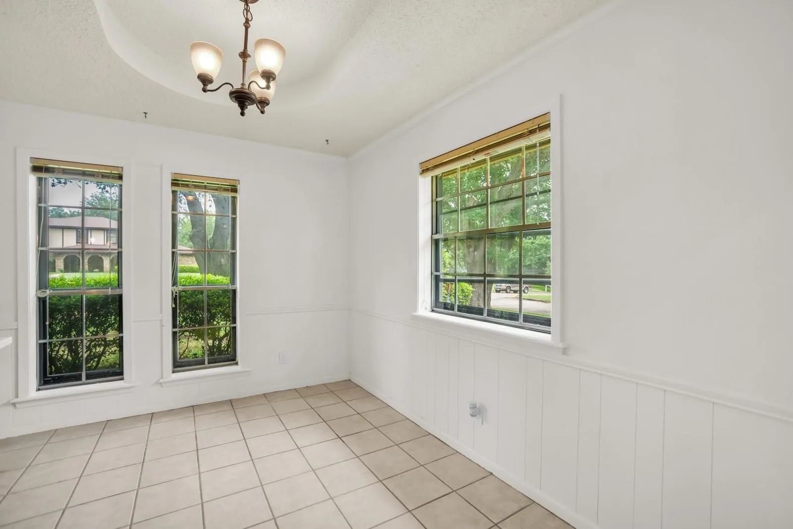 Room featuring white walls, white wainscoting, and large windows