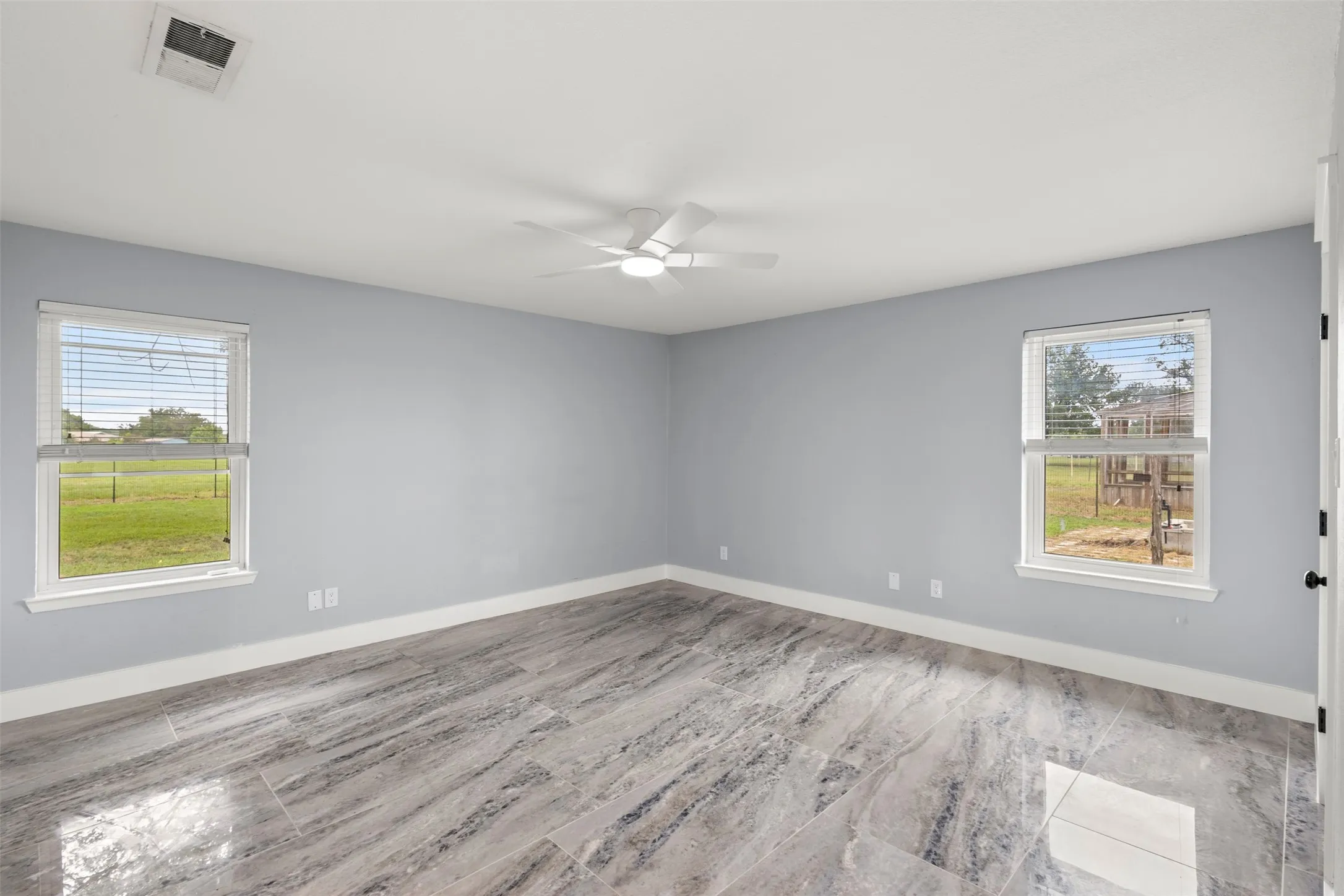 Spacious room featuring wood-look tile flooring, light gray walls, and white trim