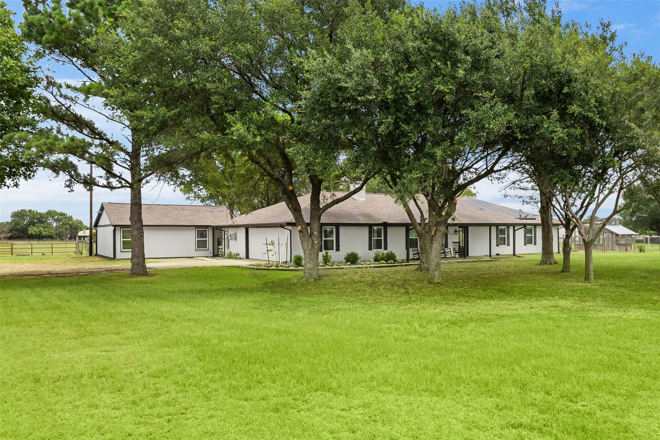 Expansive front lawn with mature trees providing natural shading