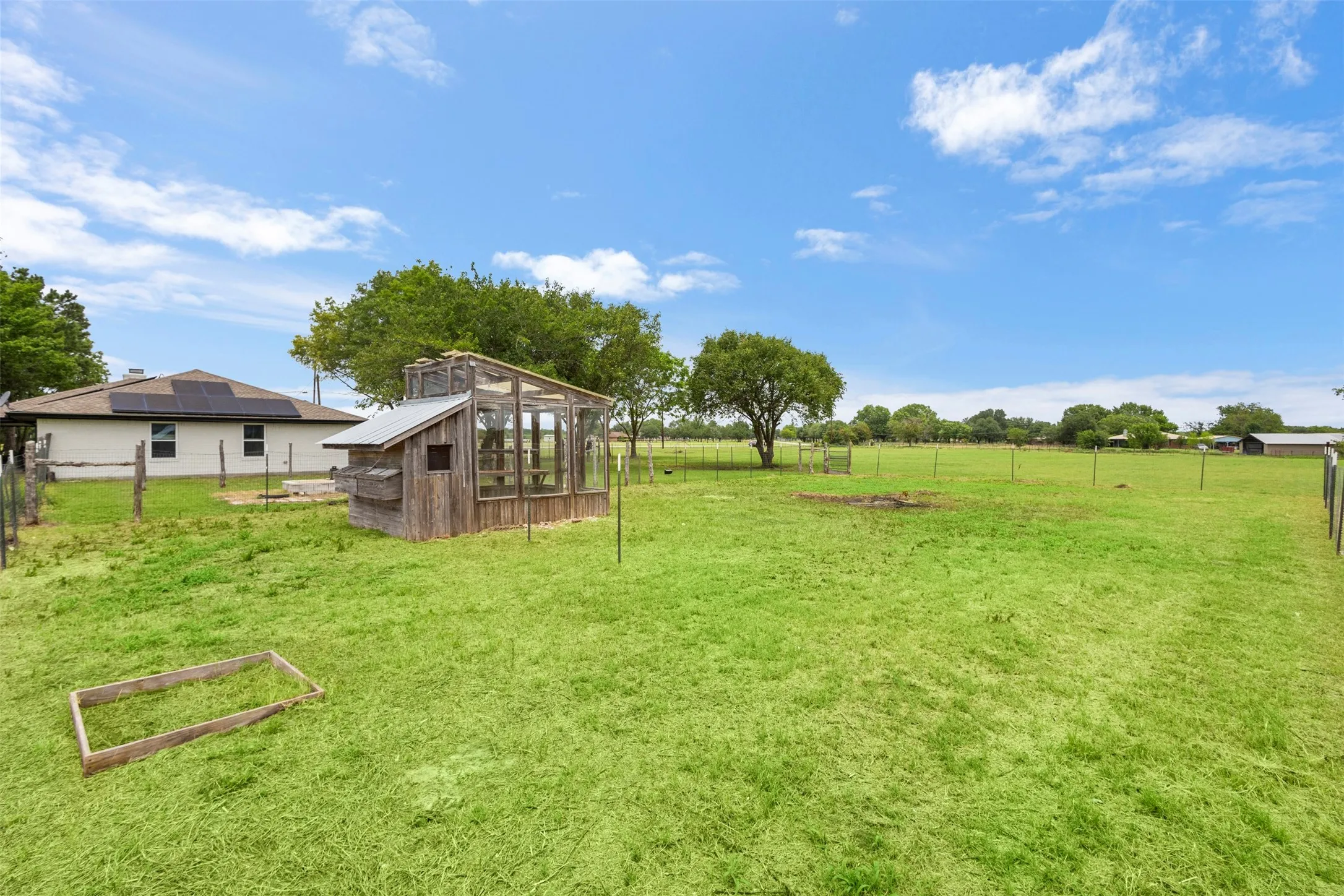 Expansive green lawn with a rustic wooden outbuilding featuring a metal roof