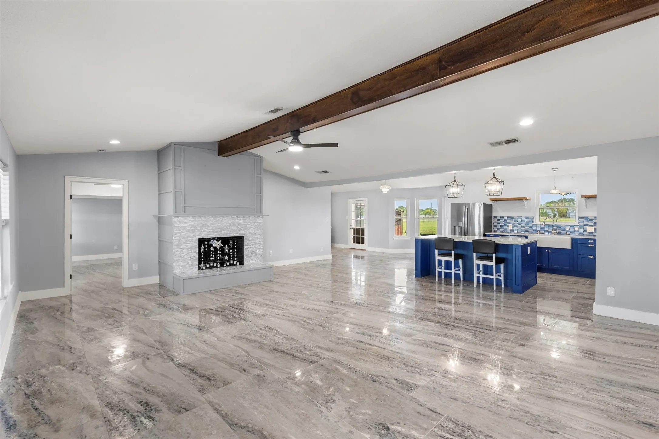 Spacious open-concept interior featuring wood-finish flooring, a contemporary fireplace with a mosaic tile surround, and a kitchen with a blue island and matching cabinetry