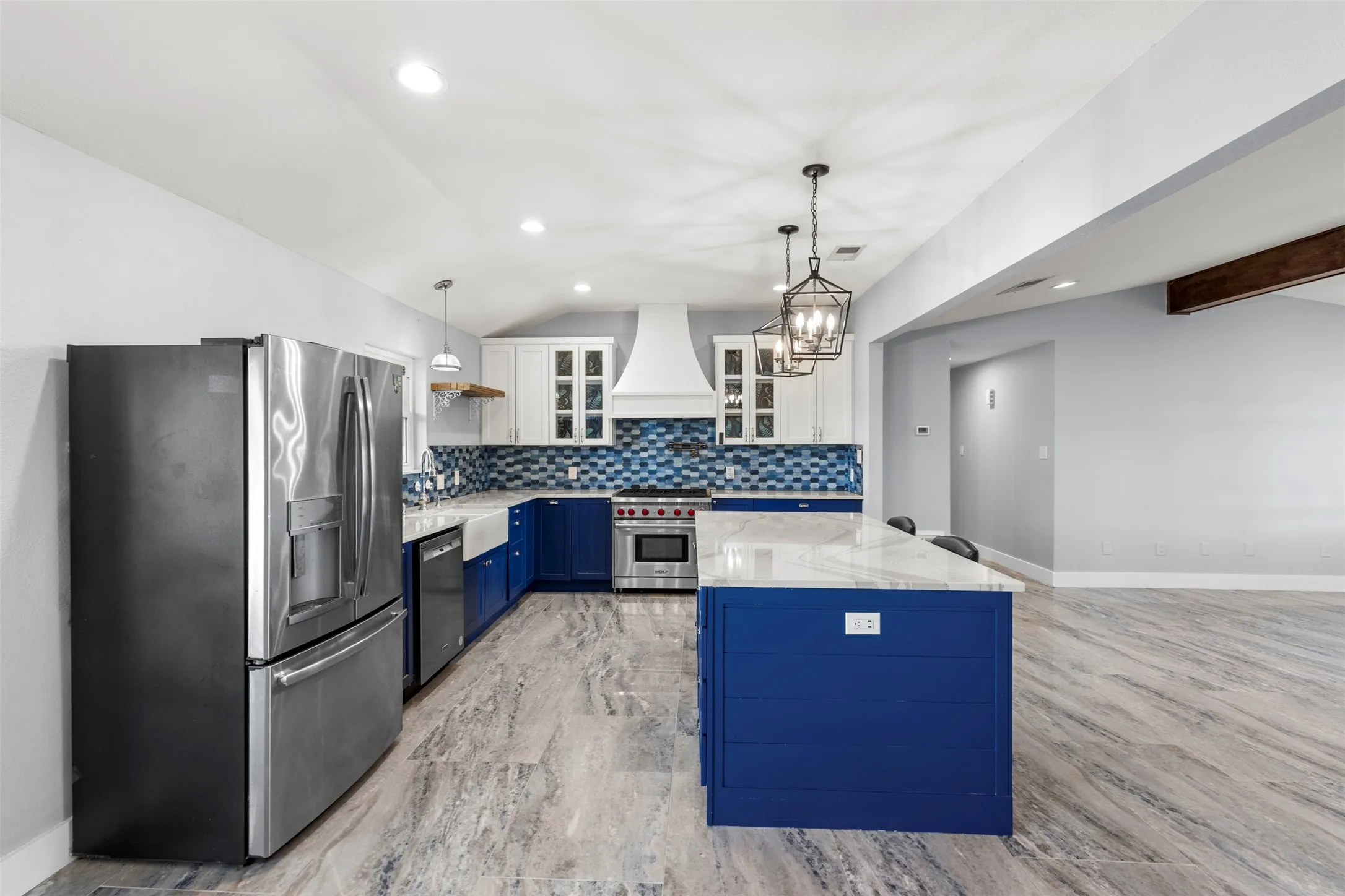 Modern kitchen featuring a blue and white color palette, stainless steel appliances, a center island with a white countertop, patterned tile backsplash, and light wood-finish flooring