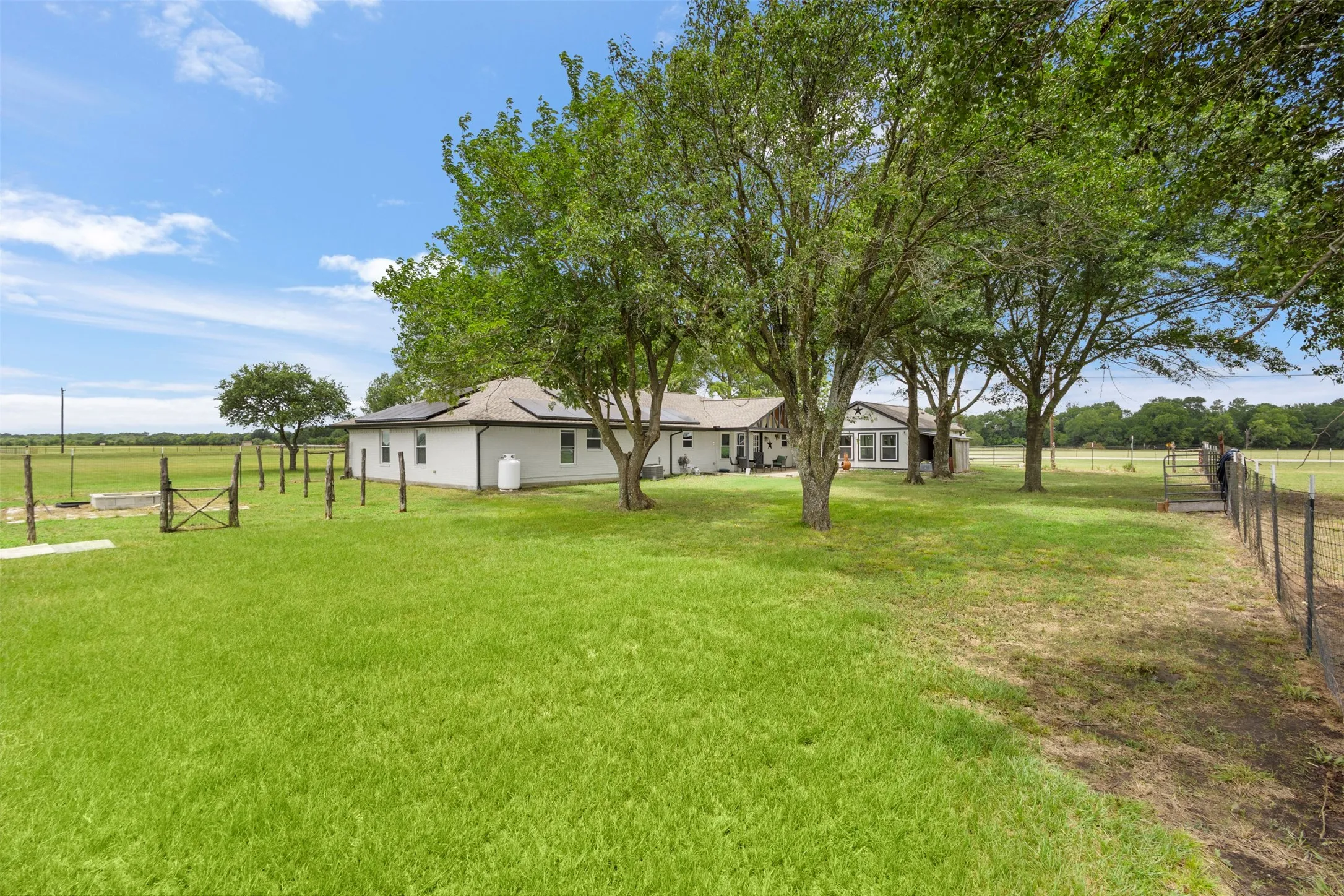 Expansive green lawn surrounds a white-sided residence with a dark roof