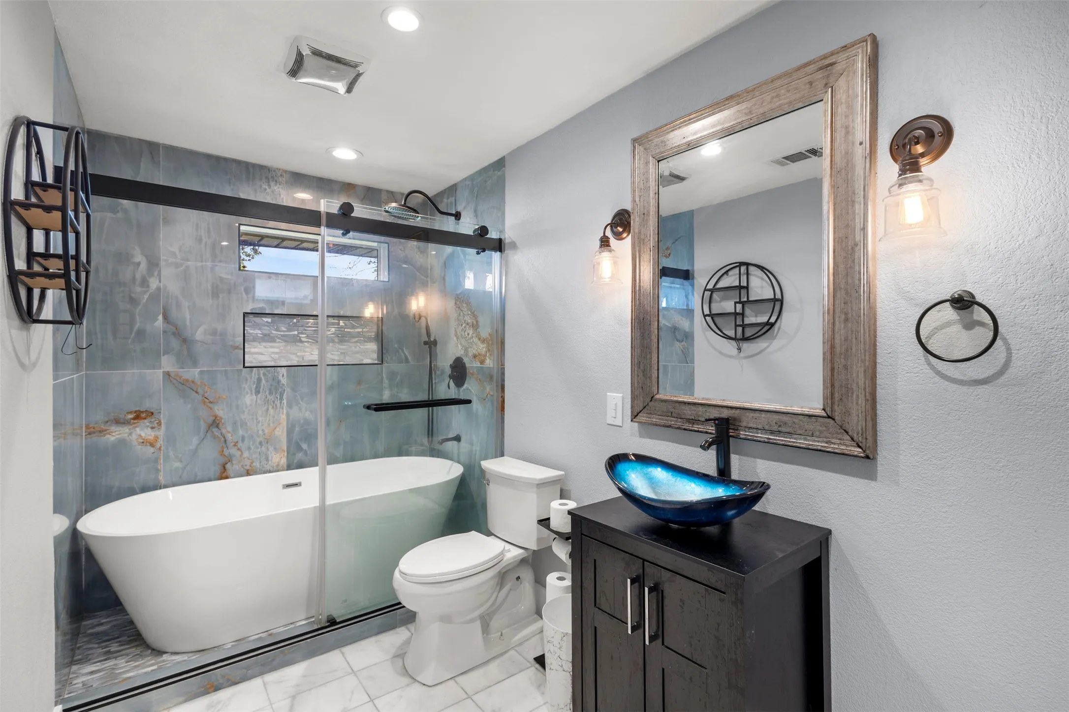 Bathroom featuring a freestanding soaking tub, clear glass shower enclosure with sliding door, and a vanity with a vessel sink