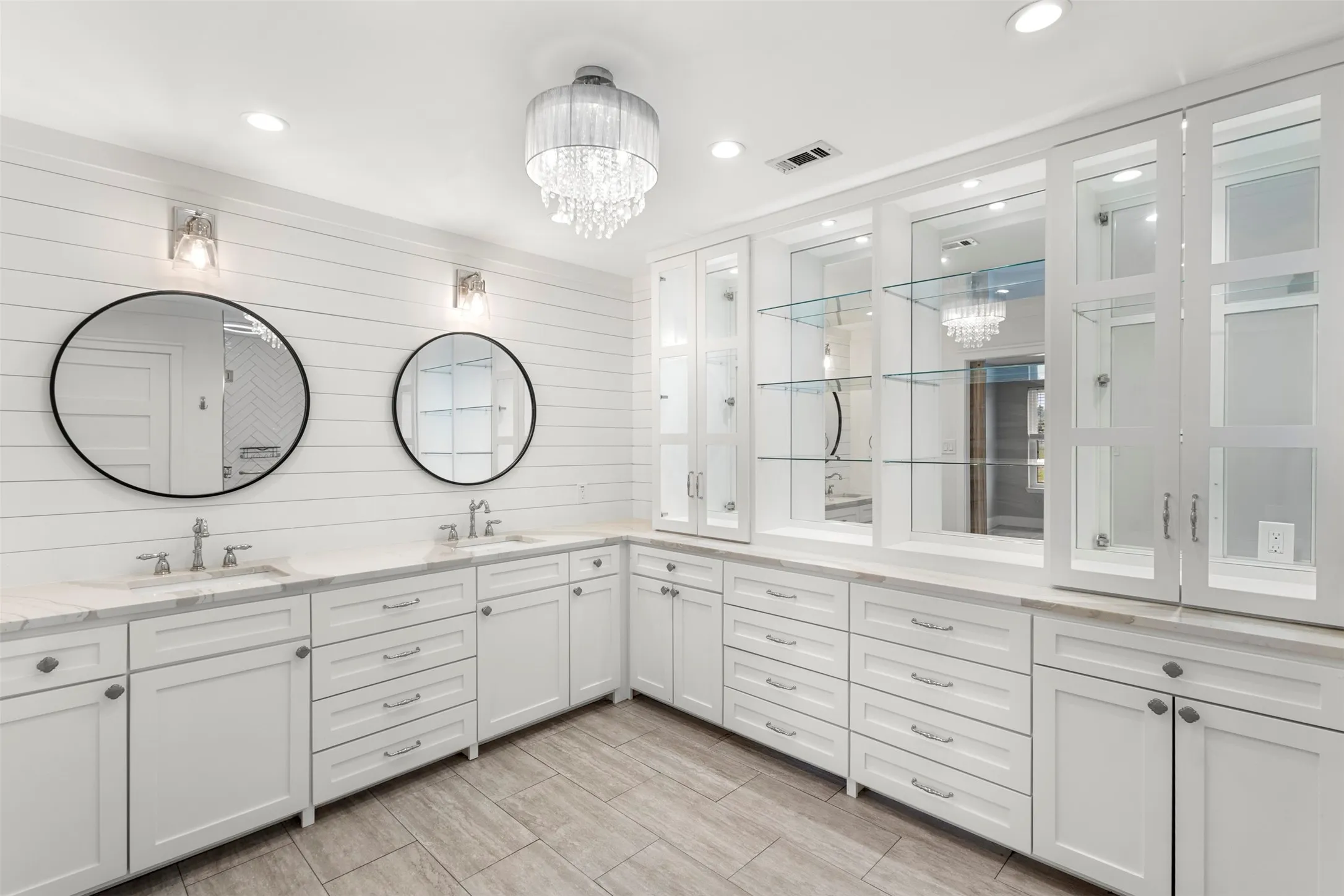 Spacious bathroom featuring dual vanities with white cabinetry and light-toned countertops