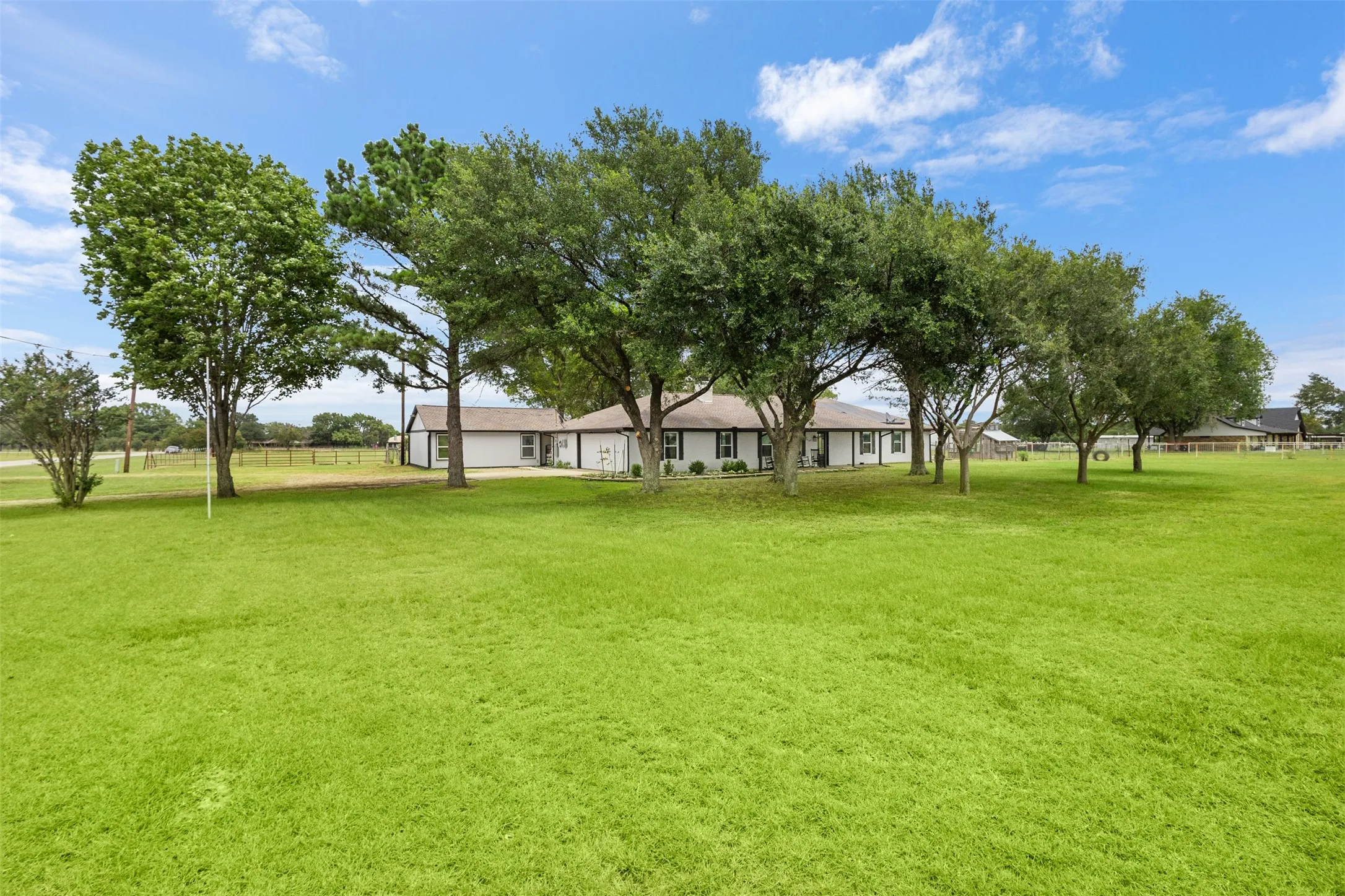 Expansive green lawn with mature trees bordering a single-story residence