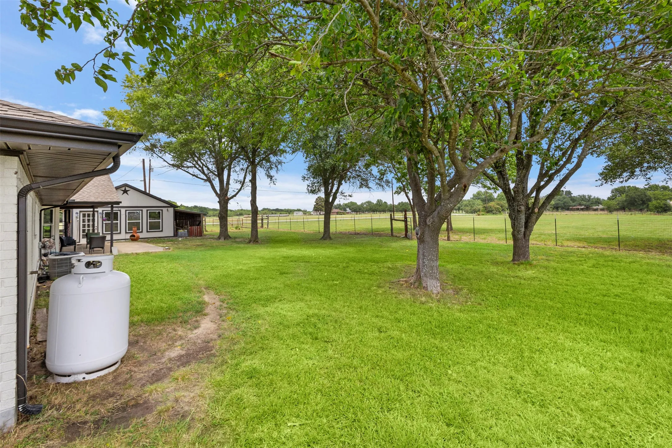 Expansive green lawn with mature trees and a fenced perimeter