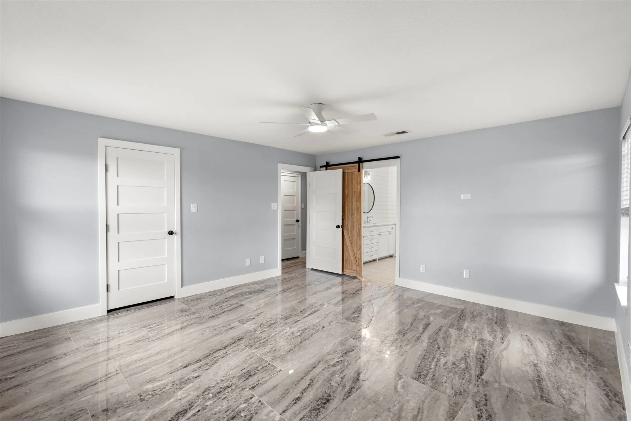 Spacious room featuring large format marble-look tile flooring, light gray wall paint, and white trim