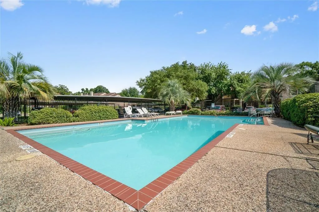 Expansive outdoor swimming pool featuring a brick coping and exposed aggregate decking