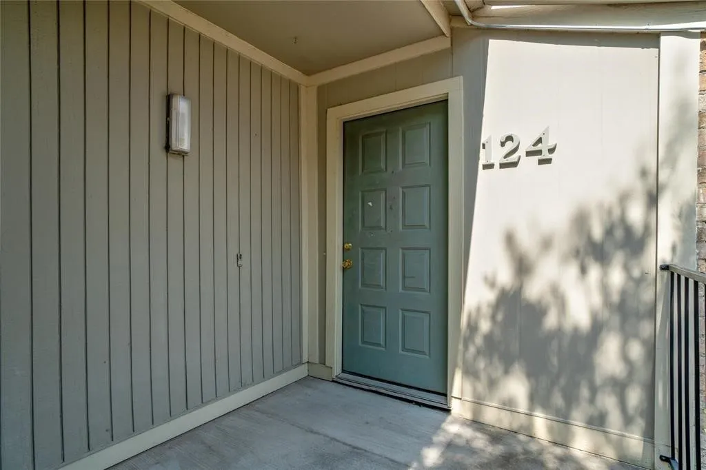 Entryway featuring a paneled door, vertical siding, and exterior lighting