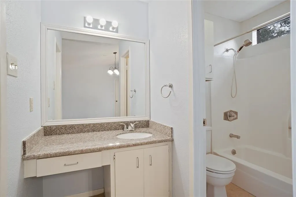 Bathroom featuring a vanity with a light-toned granite countertop, under-mount sink, and framed mirror