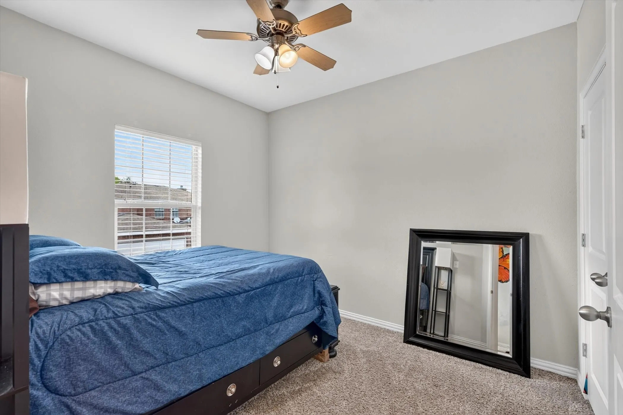 Neutral wall color with textured carpeting and a window featuring horizontal blinds