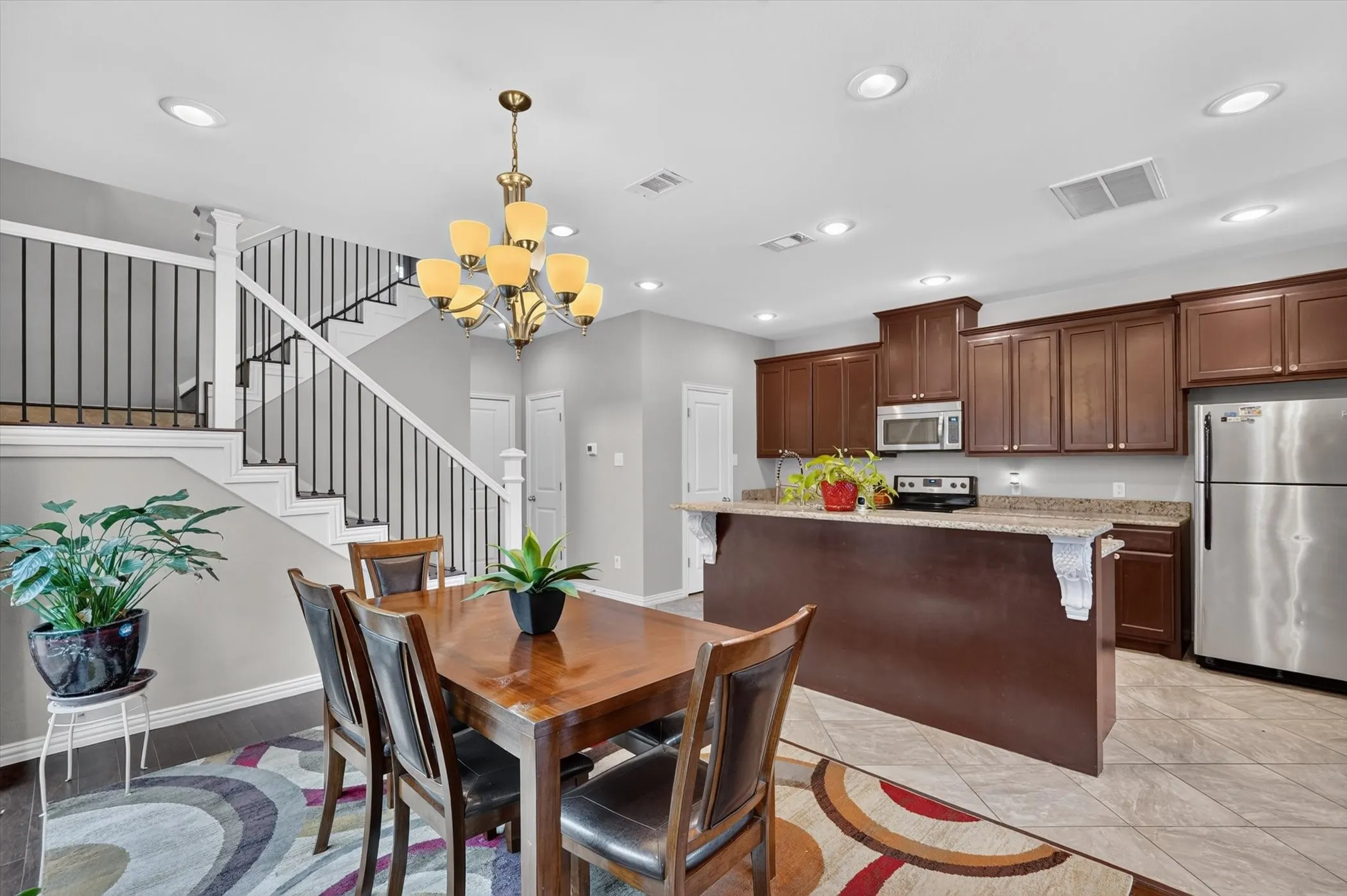 Open concept living area featuring a kitchen with dark wood cabinetry, stainless steel appliances, and stone countertops