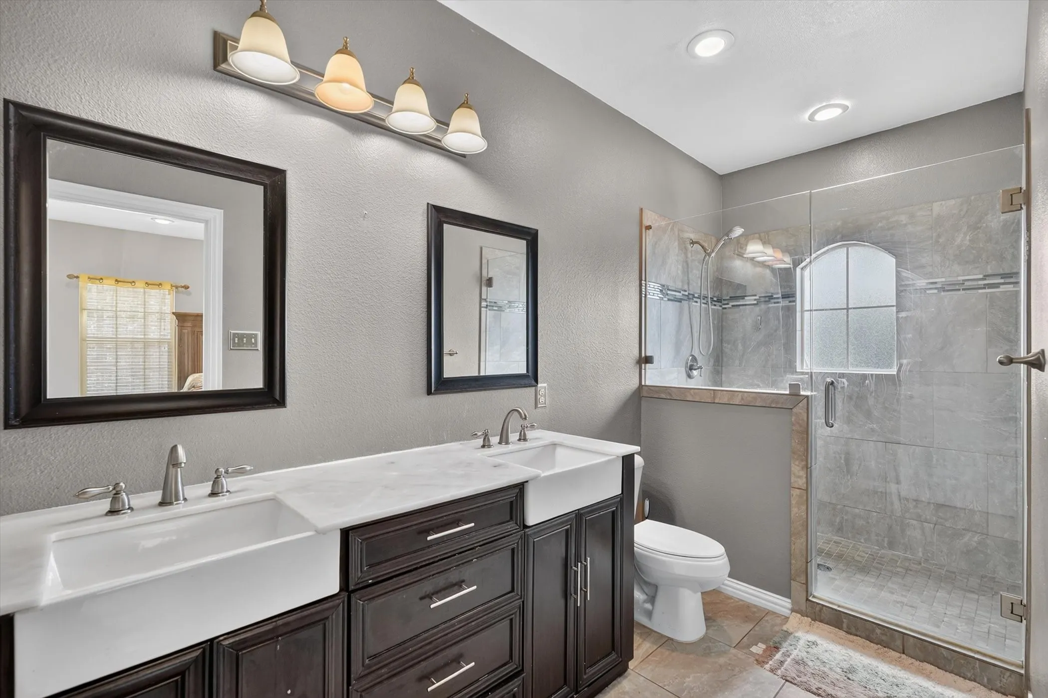 Double vanity with dark wood cabinetry, white farmhouse sinks, and chrome fixtures