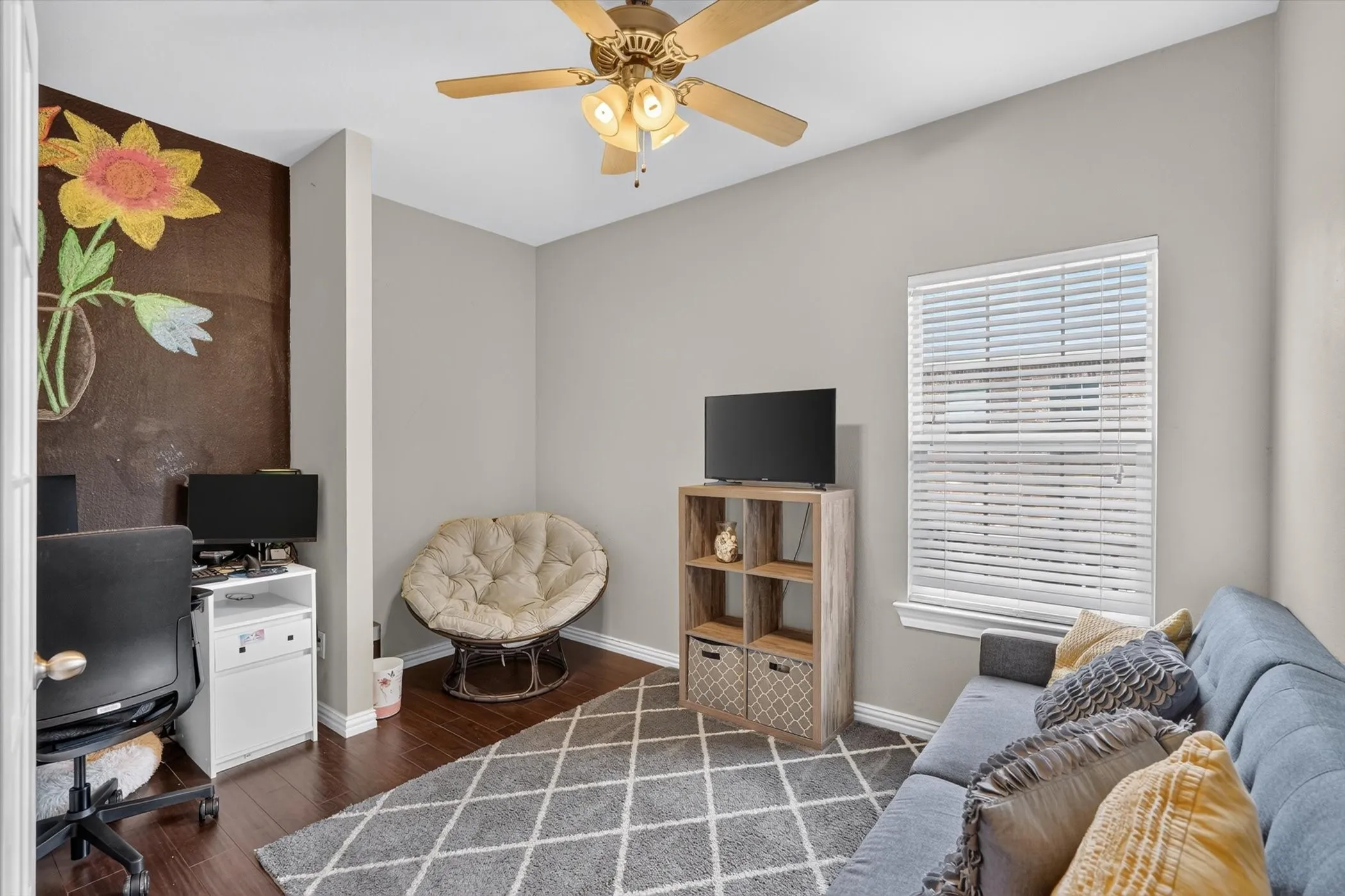 Versatile room featuring wood-finish flooring, a ceiling fan with integrated lighting, a window with horizontal blinds, and neutral wall tones