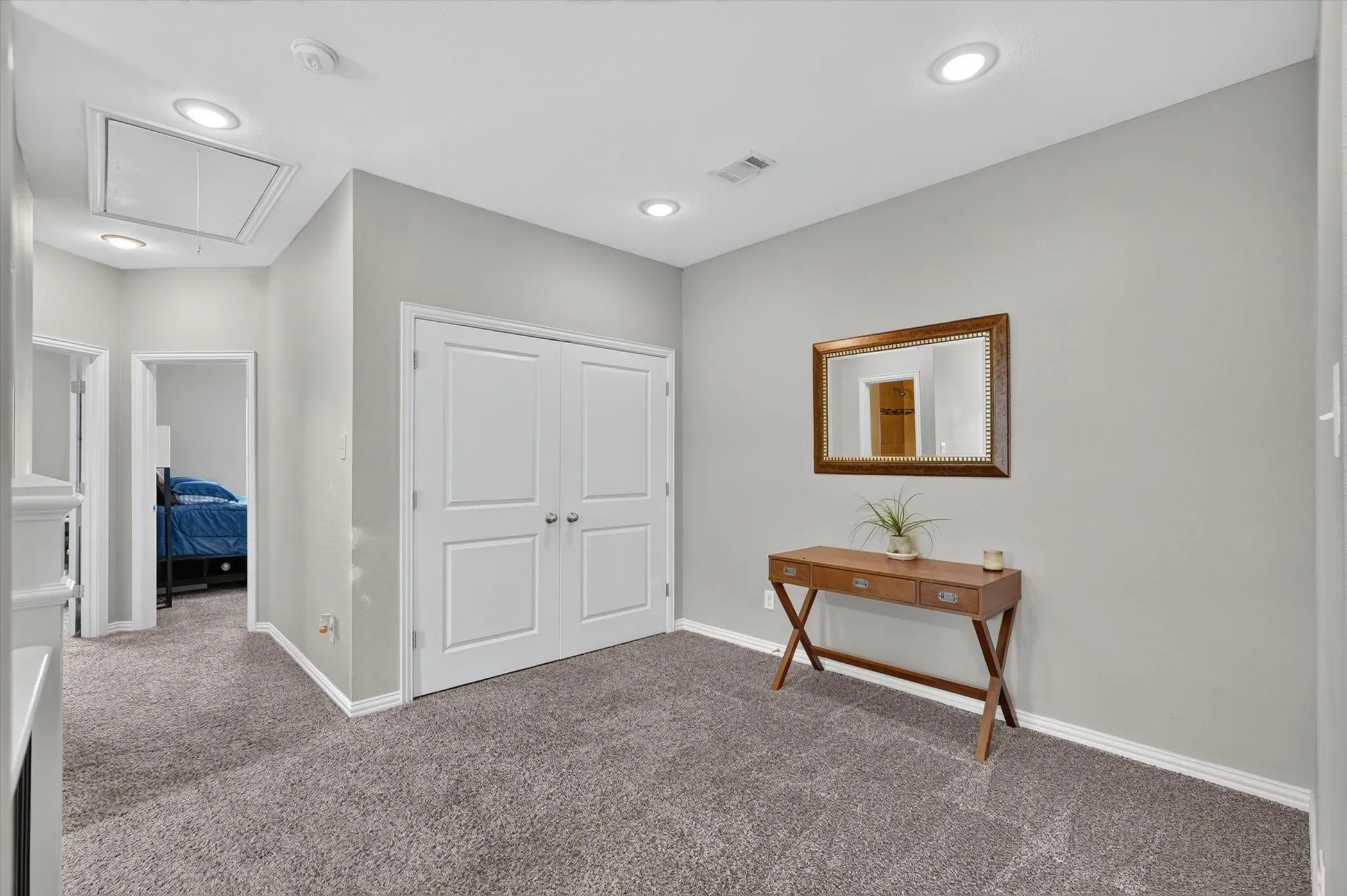 Hallway featuring plush gray carpet, white trim, recessed lighting, and a double-door closet