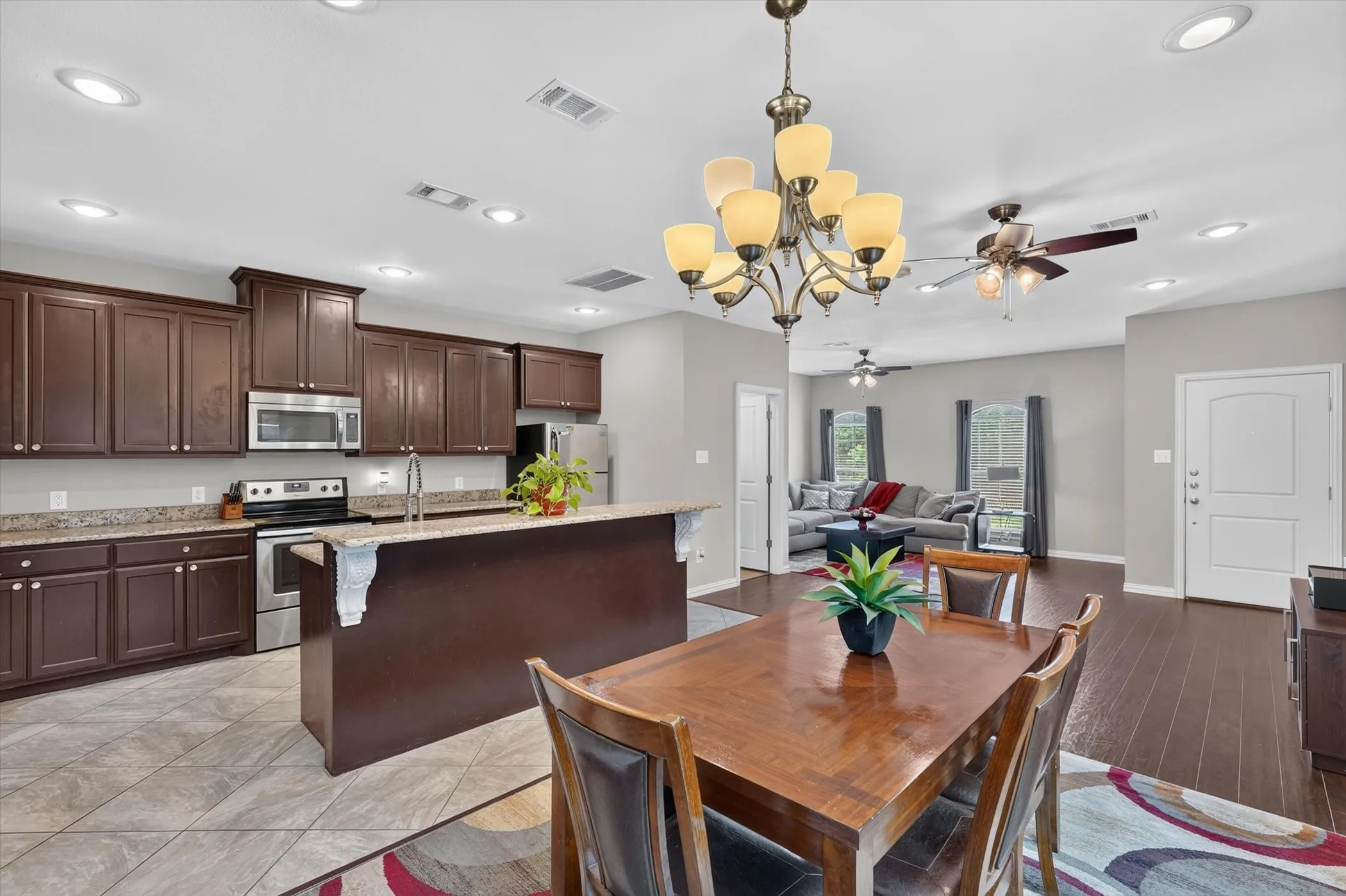 Open-concept living space featuring a kitchen with dark wood-finish cabinetry, stainless steel appliances, and a breakfast bar