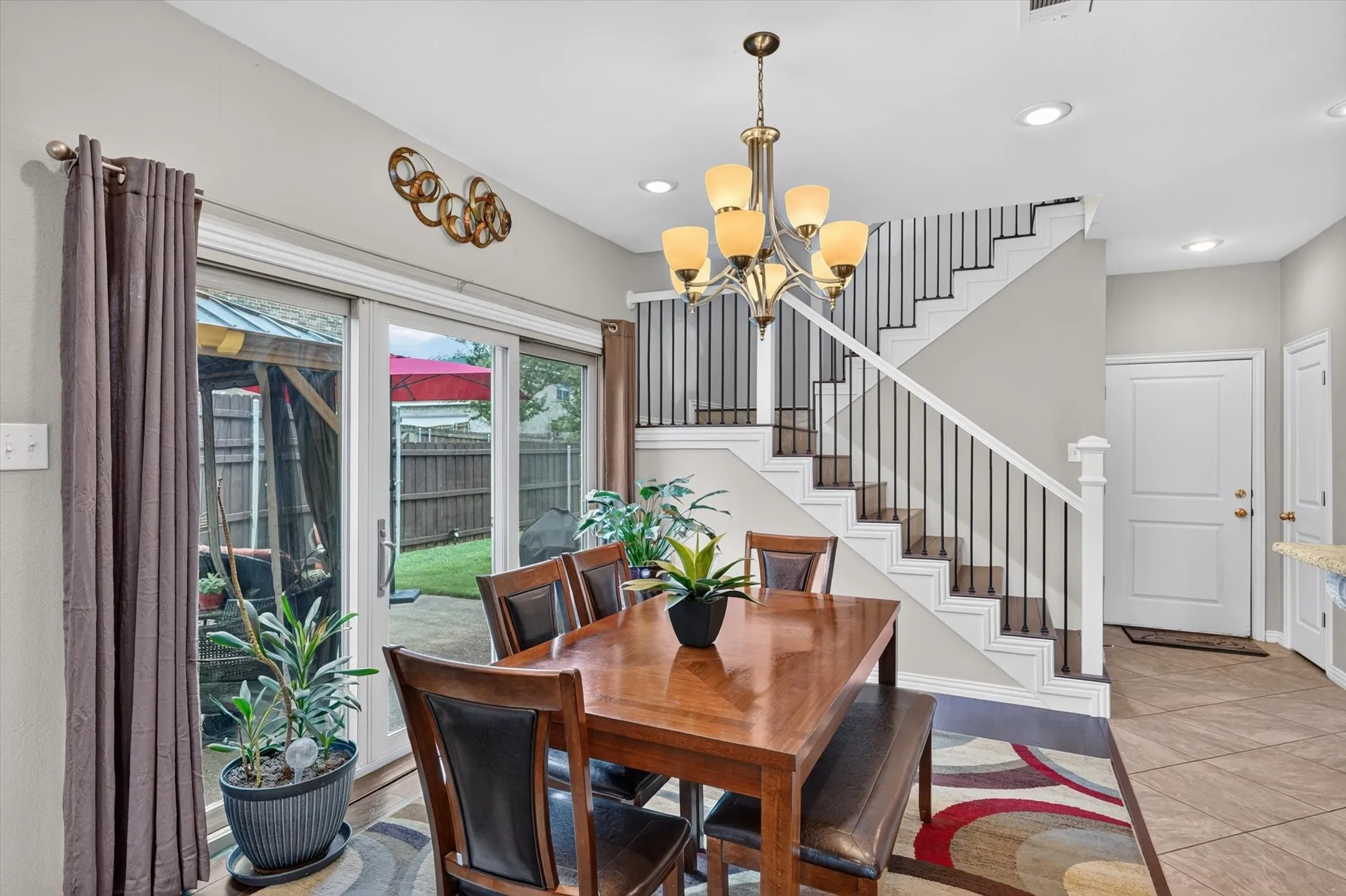 Dining area featuring sliding glass doors to the backyard, a multi-tier chandelier, and an open staircase with dark balusters