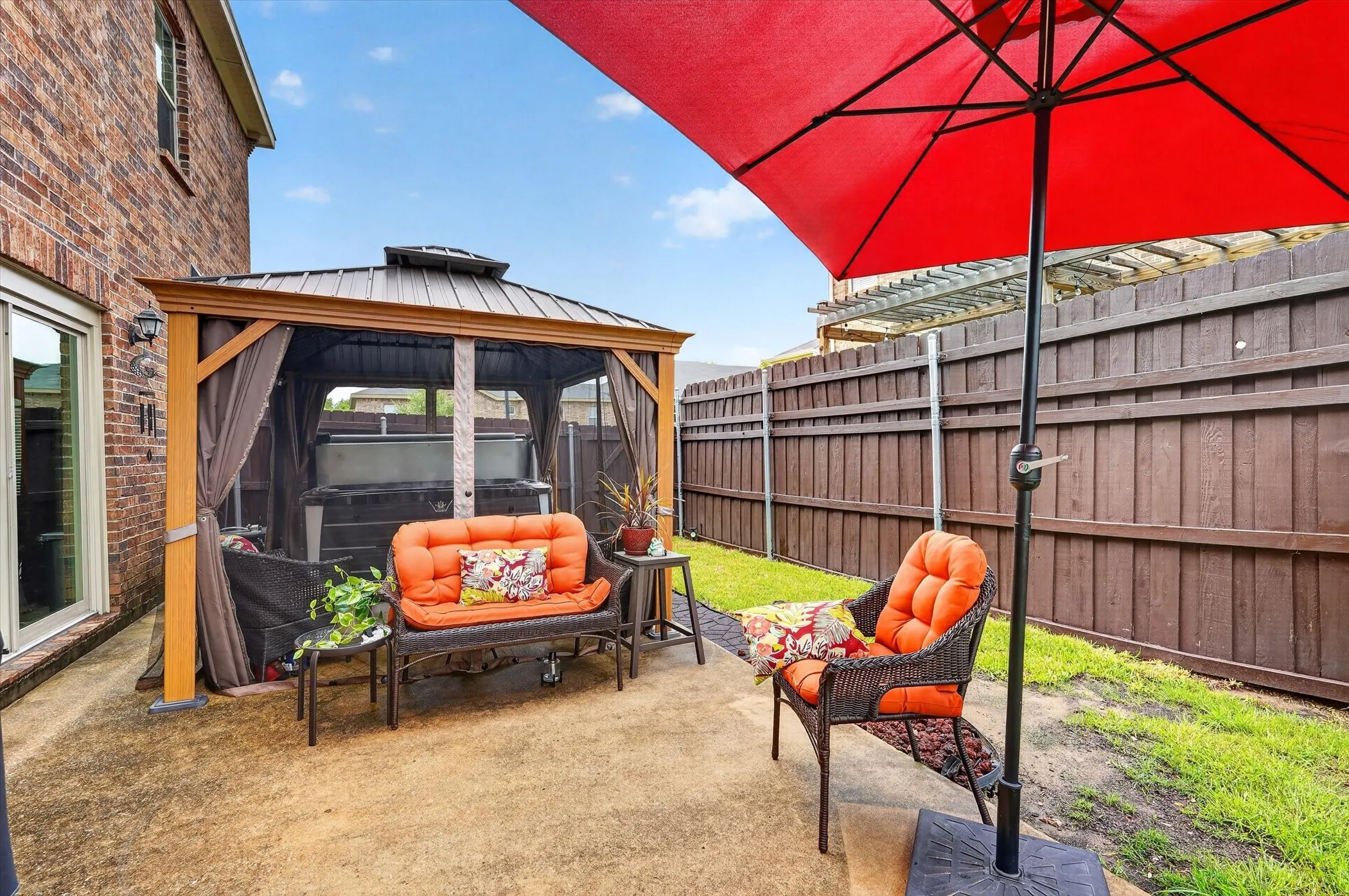Private backyard featuring a concrete patio, a screened gazebo, and a raised wooden fence