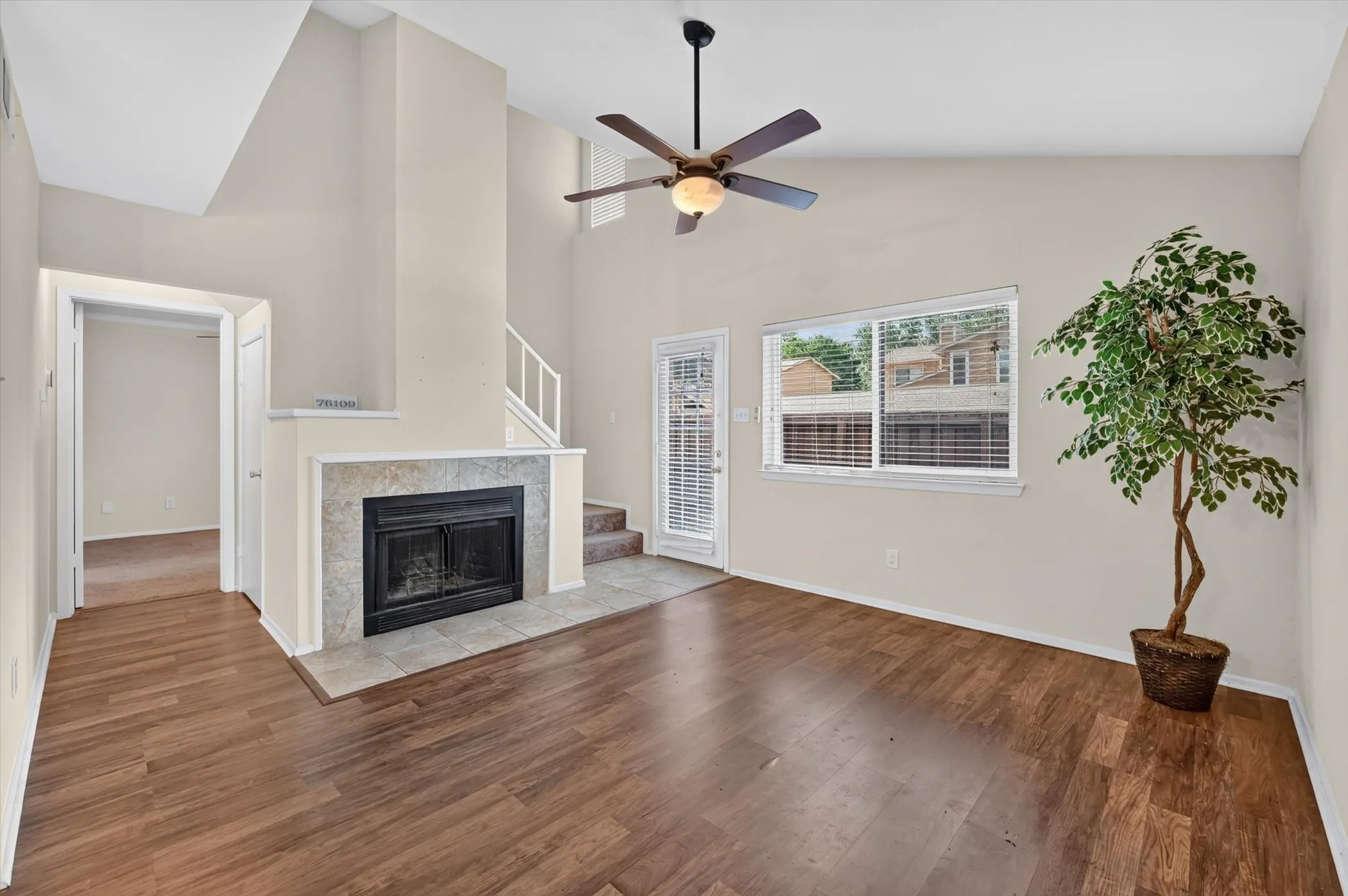 Open living area featuring wood-finish flooring, a tile-surround fireplace, and a ceiling fan