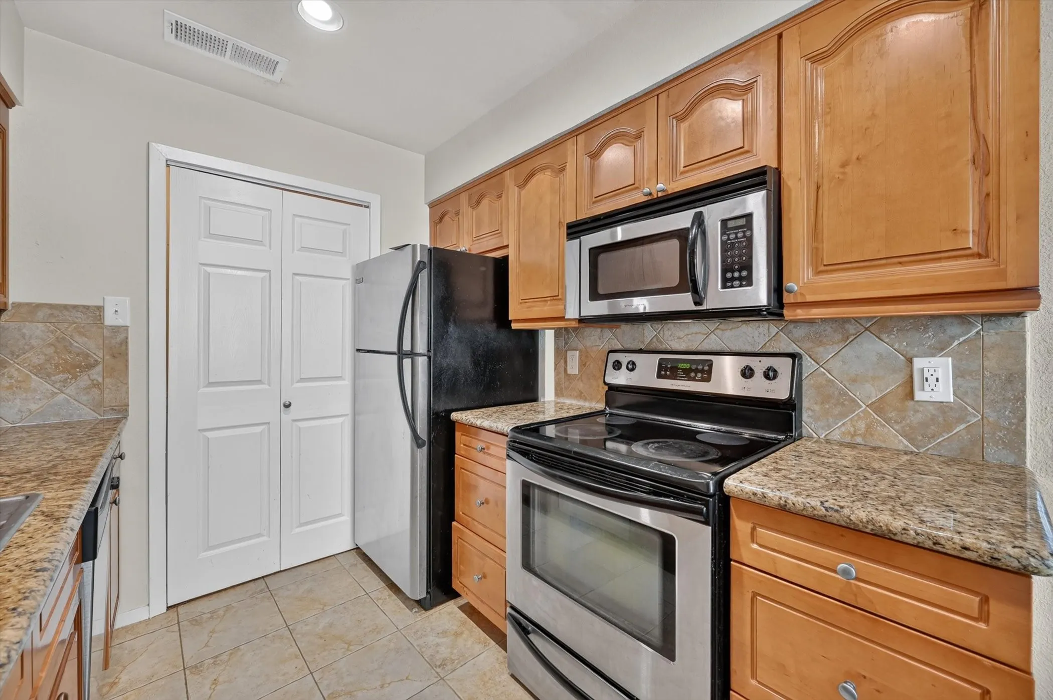 Kitchen featuring wood cabinetry, granite-style countertops, and a tiled backsplash